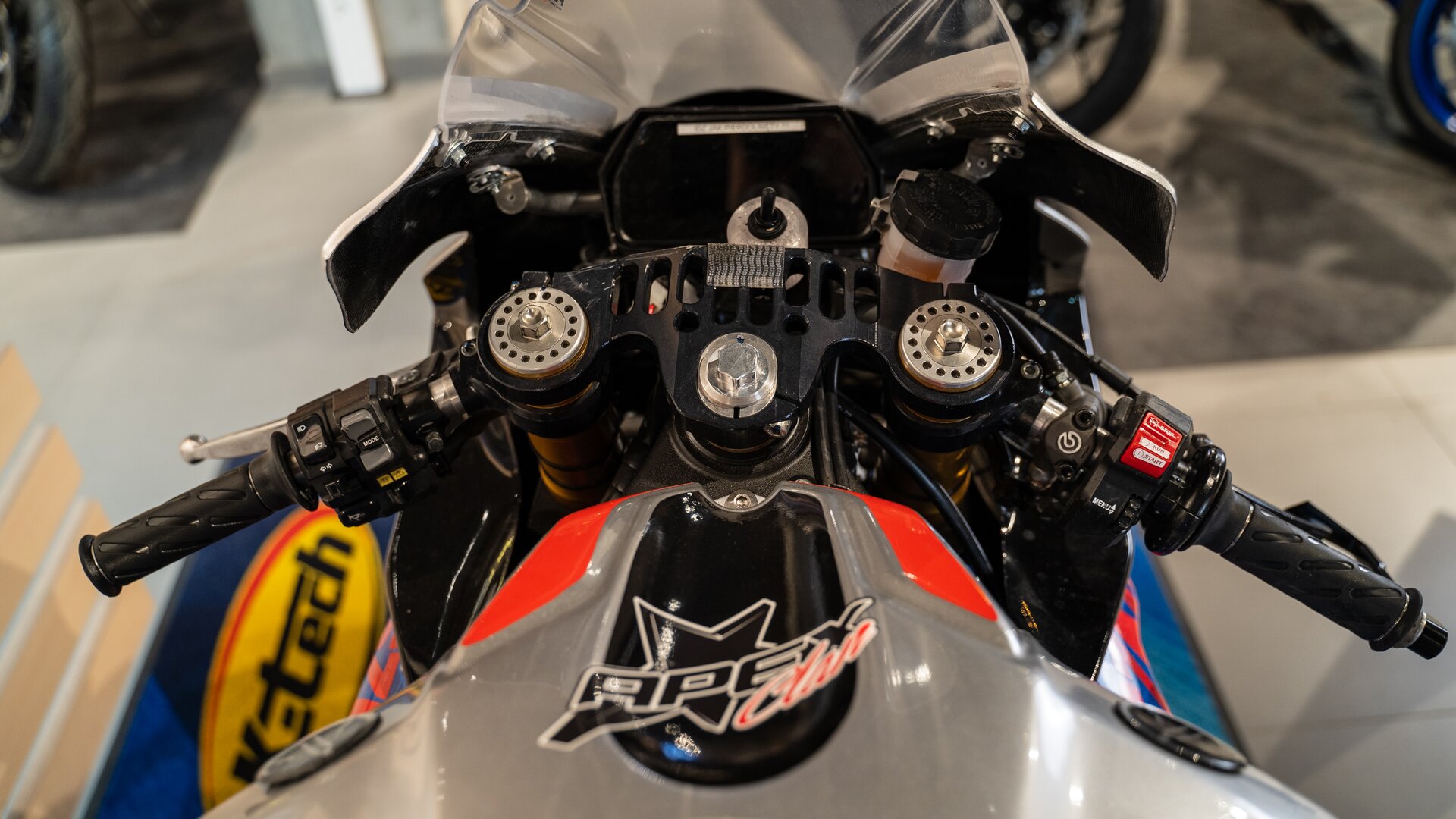 Zdjęcie ukazuje zbliżenie na kierownicę motocykla. W pobliżu uchwytów kierownicy są przyciski, hamulce. 