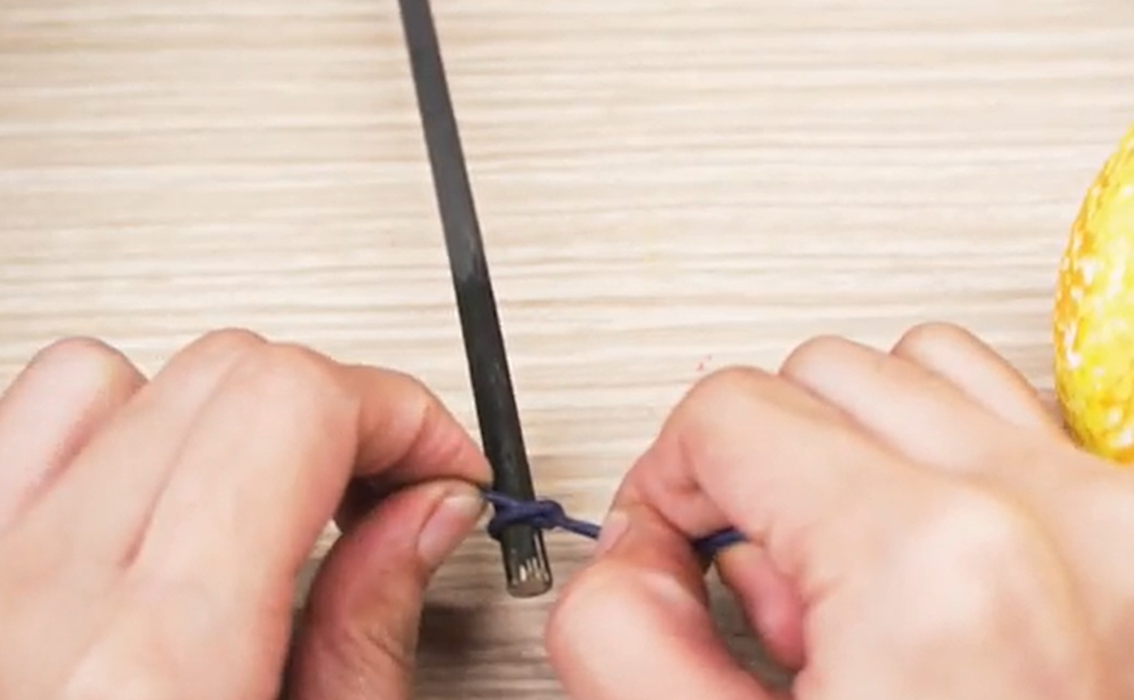 Zdjęcie przedstawia wiązanie sznurka na pomalowanym patyku.