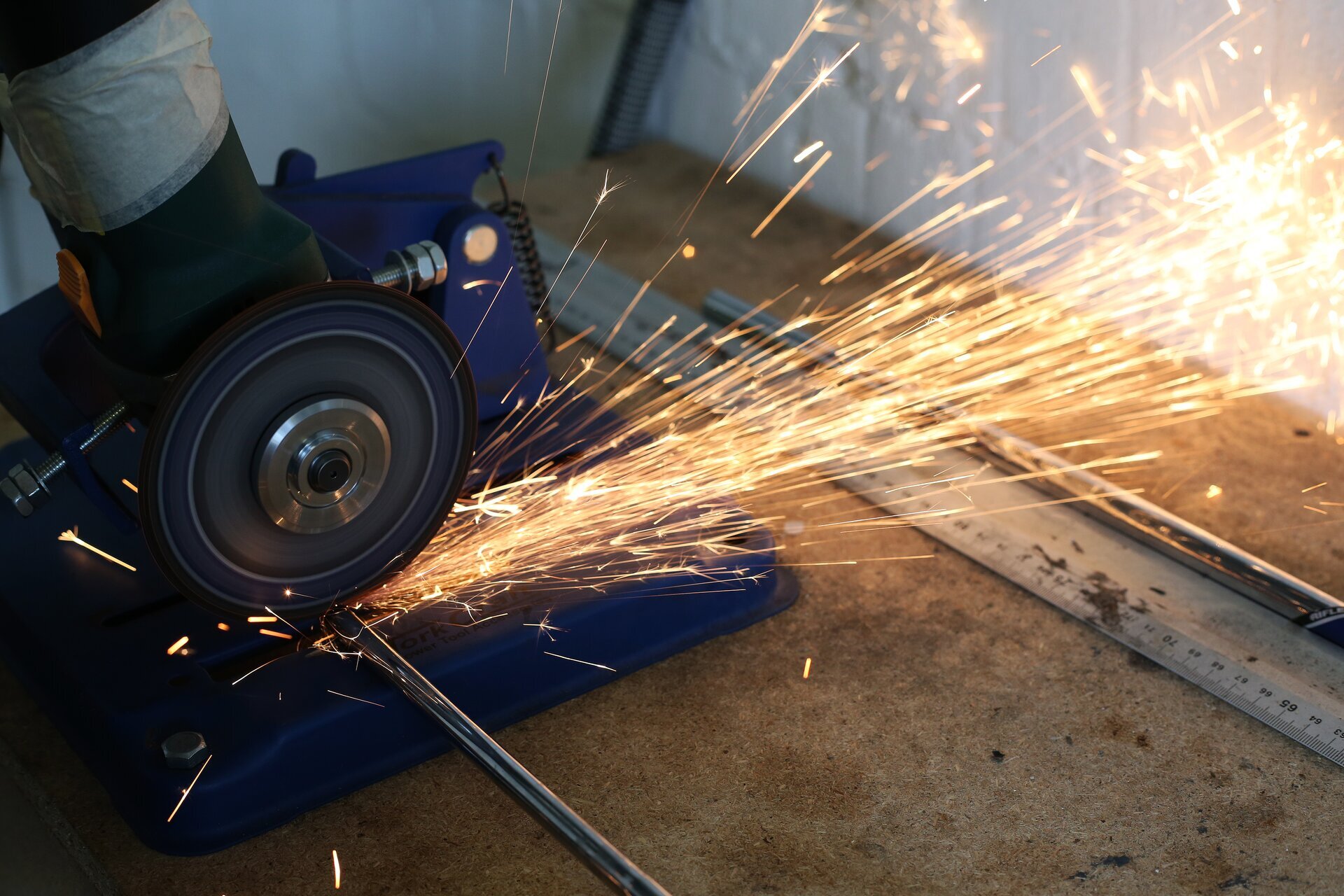 Zdjęcie przedstawia szlifierkę kątową przecinającą stalowy pręt.