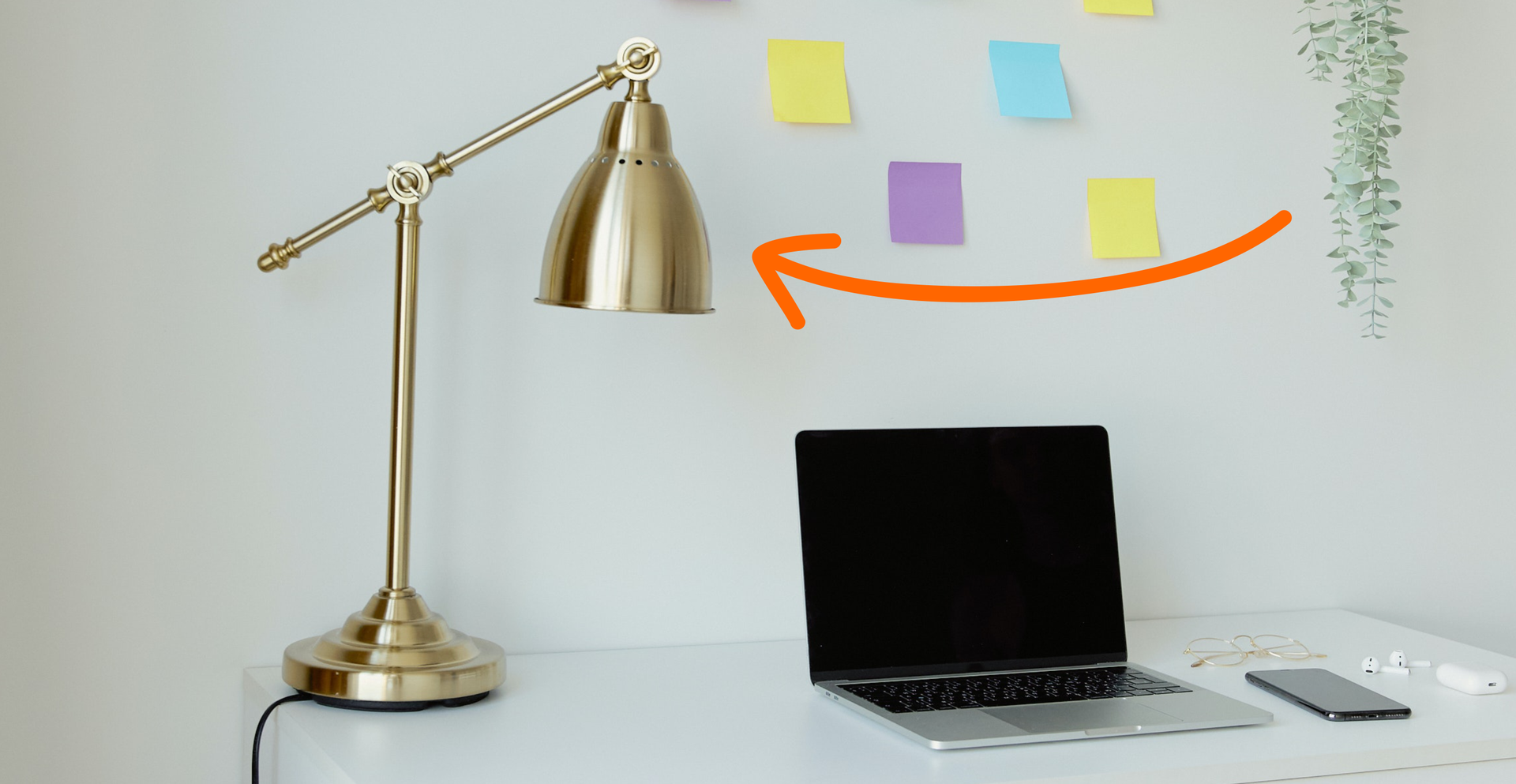 Zdjęcie przedstawia biurko, na którym znajduje się lampka oraz komputer. Strzałka na ilustracji skierowana jest na lampę.