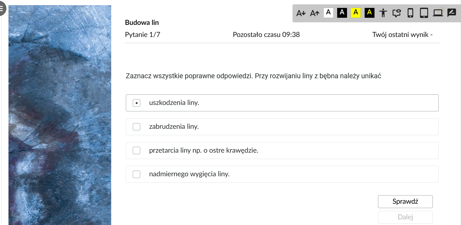 Grafika przedstawia przykładowe zadanie testowe. Ponad poleceniem widać numer pytania, czas, który pozostał na wypełnianie testu, oraz ostatni uzyskany wynik. Pod poleceniem znajdują się możliwe odpowiedzi. W prawym dolnym rogu panelu z zadaniem znajdują się dwa przyciski. Są to Sprawdź oraz Dalej.