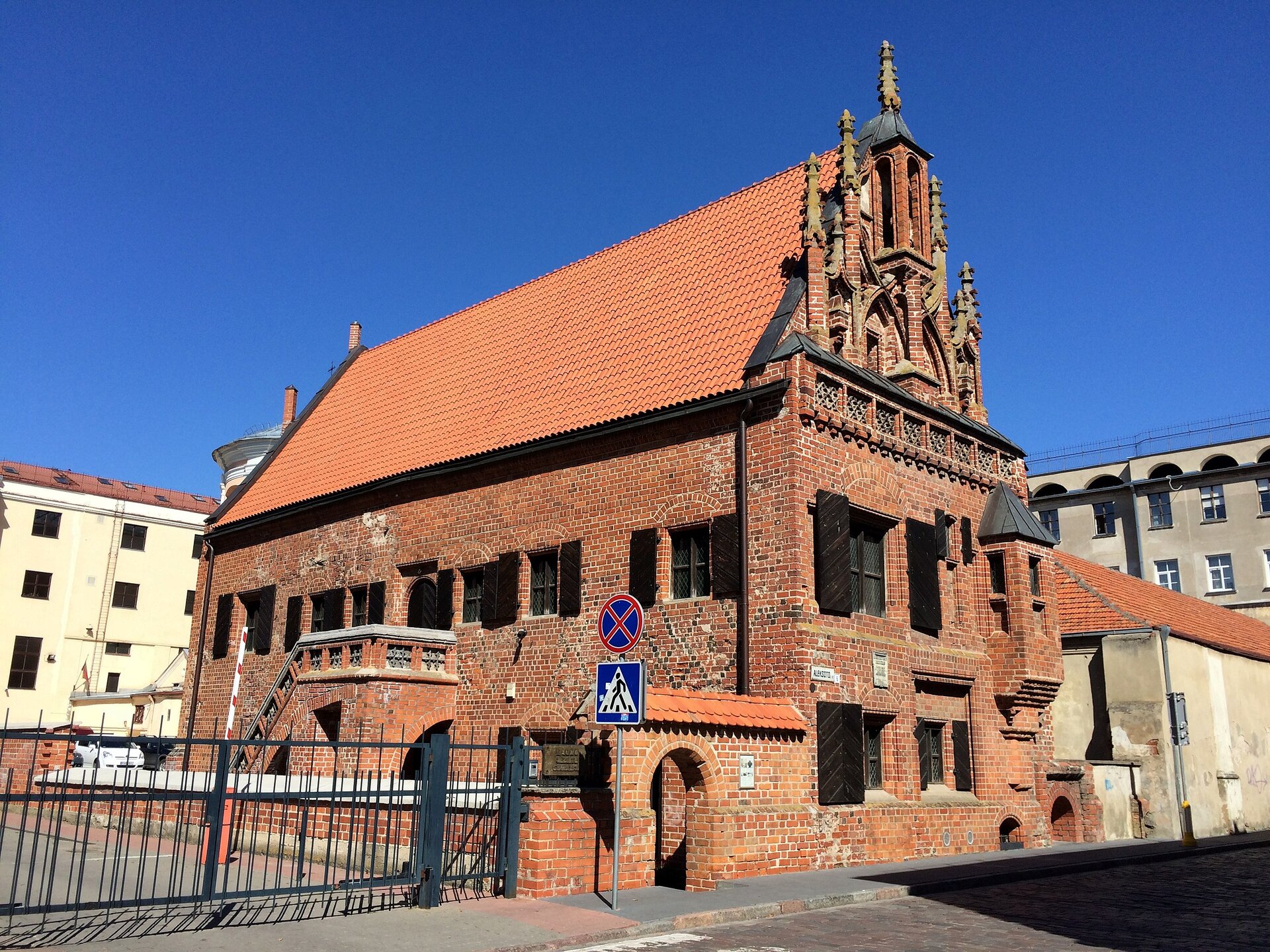 Na zdjęciu budynek z czerwonej cegły. Ma strzelisty dach.