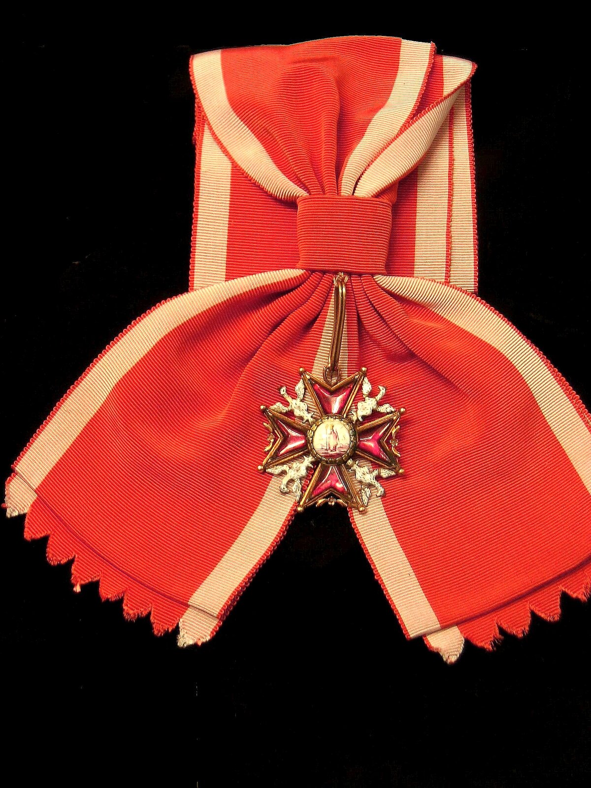 Order Świętego Stanisława. Czerwona wstążką z jasnymi paskami, która związana gumką dzieli się na dwie odnogi. Do gumki przyczepiona zawieszka, a na końcu jej krzyż. Pomiędzy ramionami orły.