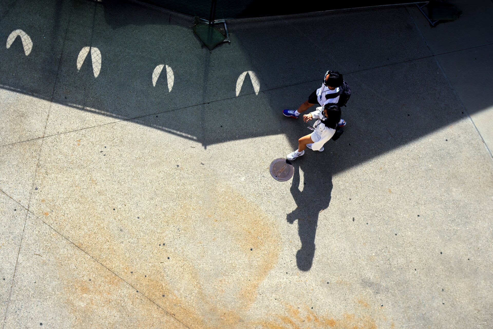 Ilustracja przedstawiona jest z lotu ptaka, która ukazuję obszar pokryty płytami modułowym. Górna część pokryta jest ciemną płytą, gdzie po lewej stronie na płytach są zamieszczone jasne małe wzory. W dolnej części fragment wyłożony jest jasną płytą. Po prawej stronie grafiki idą dwie osoby.