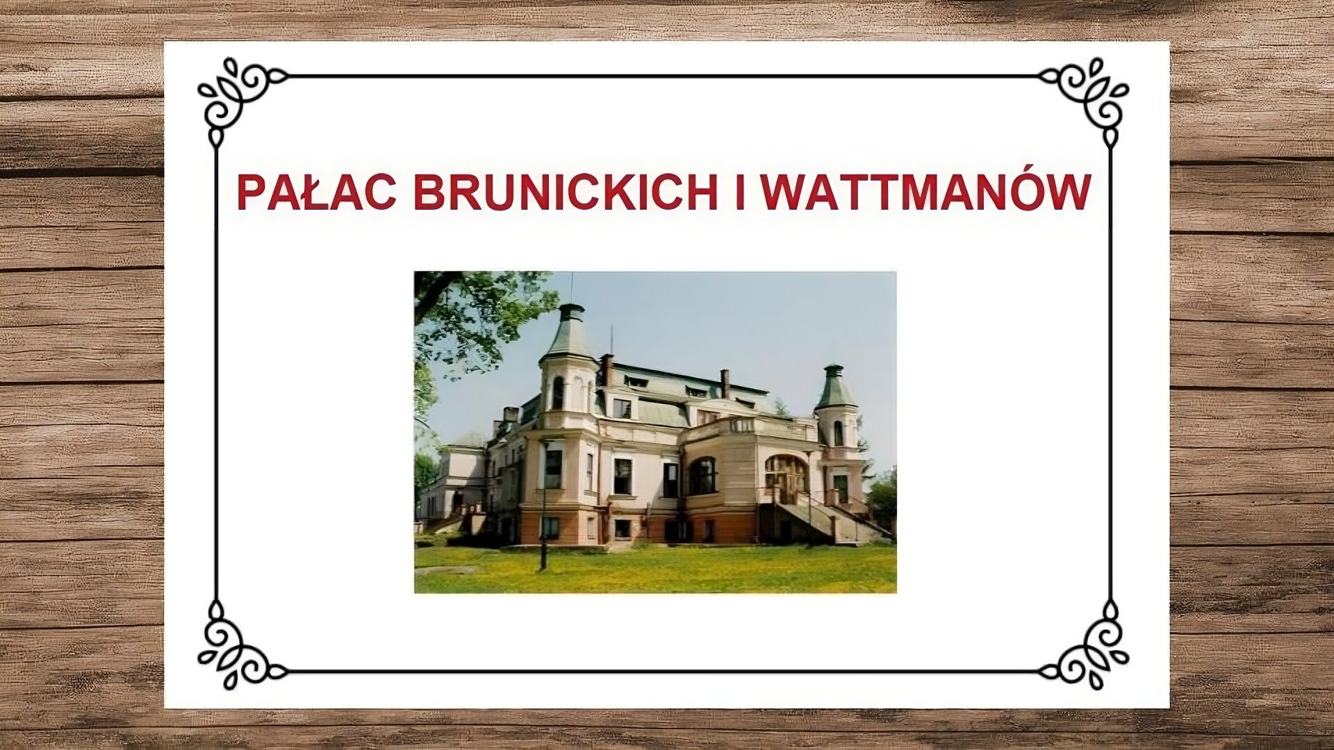 Plansza przedstawiająca drewniane deski, na których leży biała karta. Na jej górze nagłówek: „Pałac Brunickich i Wattmanów”. Poniżej zdjęcie przedstawiające widok na pałac w Rudzie Różanieckiej. Ukazana jest zachodnia i południowa fasada pałacu z narożnymi dwoma wieżami, które nakryte są hełmami z blachy. Od strony zachodniej fasada ma w centralnej części zamkniętą werandę ze schodami prowadzącymi w stronę ogrodu. Schody ocienione są metalową balustradą wspartą na kamiennych cokołach. Dach mansardowy ma dwie facjatki i na poziomie pierwszego piętra jest otwarty na taras balkonowy zamknięty kamienną balustradą. Zlokalizowana po lewej stronie fotografii fasada południowa również ma pośrodku werandę i schody tej samej konstrukcji, co po stronie zachodniej. Przed wieżą południowo‑zachodnią jest latarnia. Wokół pałacu rozciąga się trawnik.