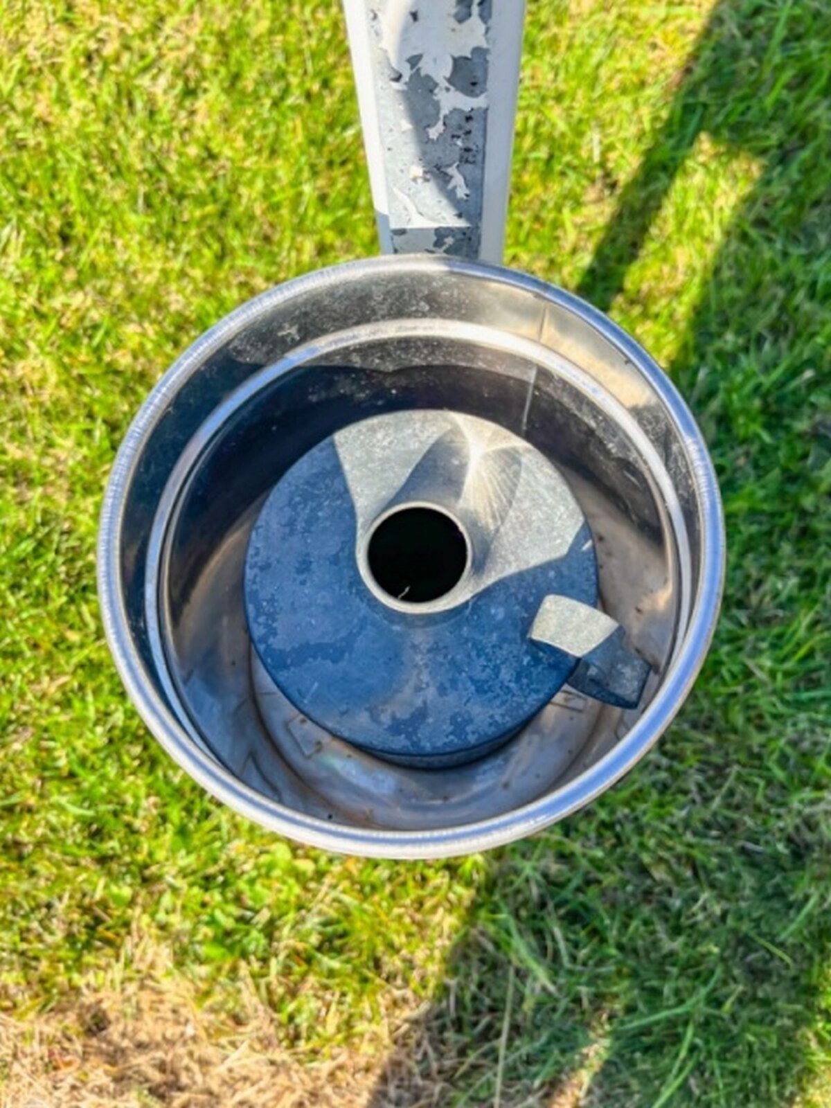 Zdjęcie przedstawia zbiornik deszczomierza do gromadzenia wody. Widać go od góry. W środku widać otwór do zbiornika.