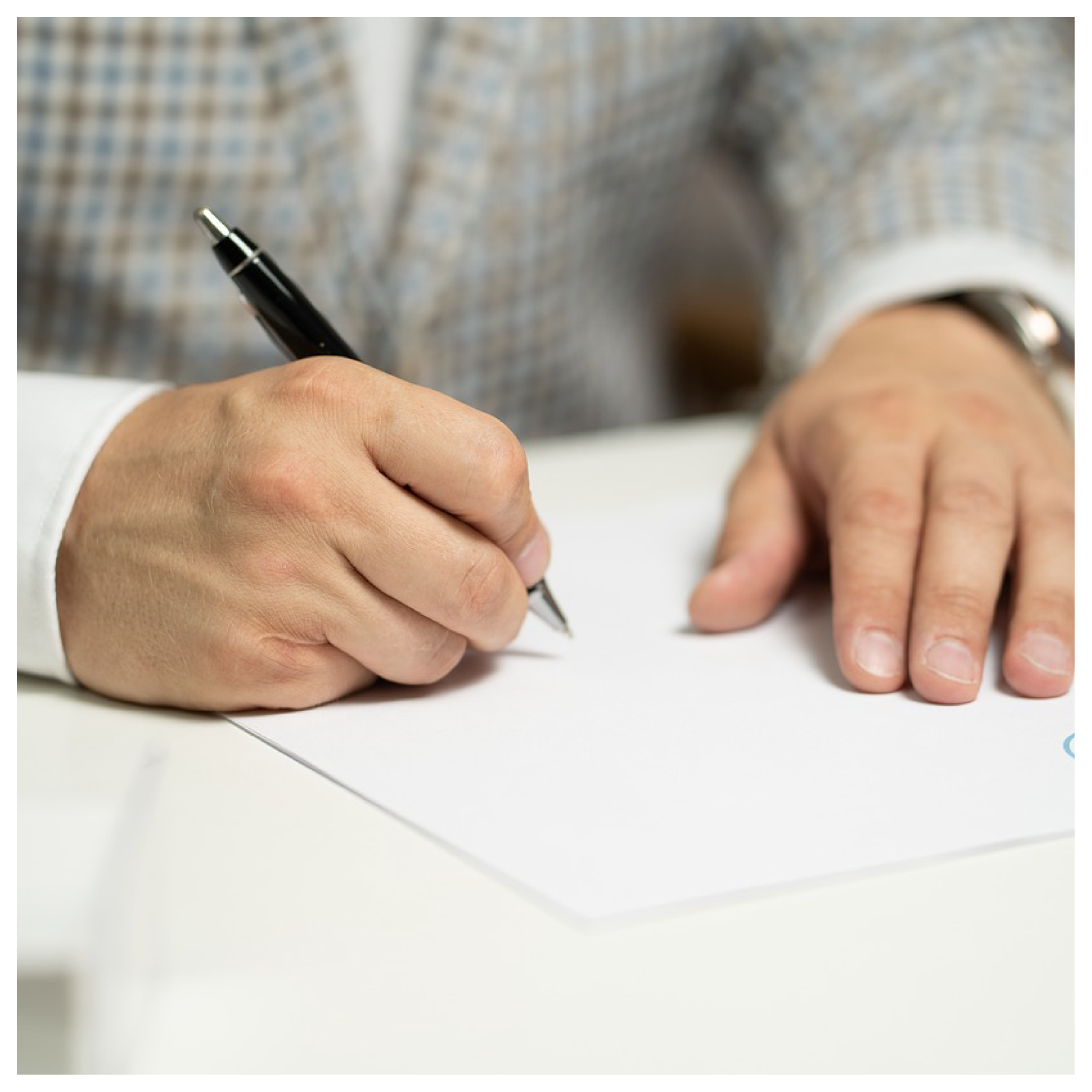 Ilustracja przedstawia fragment sylwetki osoby w marynarce piszącej coś na kartce przy stole.