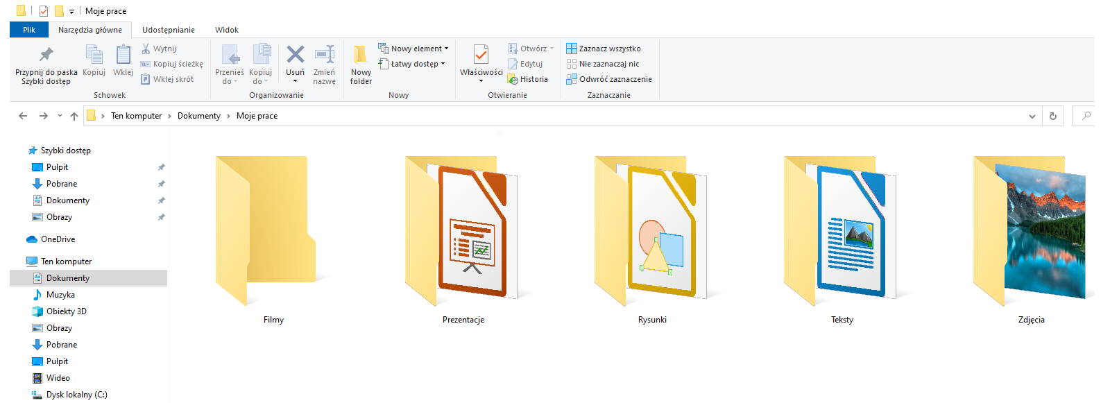 Zrzut ekranu Eksploratora plików z otwartym folderem "Moje prace" znajdującym się w "Dokumentach" w "Ten Komputer". W prawym górnym rogu znajduje się nazwa bieżącego otwartego folderu "Moje prace", poniżej znajdują się zakładki "Pliki", "Narzędzia główne", "Udostępnianie", "Widok". W zakładce "Narzędzia główne" eksploratora plików znajdują się narzędzia: w sekcji "Schowek" - "Przypnij do paska; Szybki dostęp", "Kopiuj", "Wklej", "Wytnij", "Kopiuj ścieżkę", "Wklej skrót". W sekcji "Organizowanie" - "Przenieś do", "Kopiuj do" "Usuń", "Zmień nazwę". W sekcji "Nowy" - "Nowy folder", "Nowy element", "Łatwy dostęp". W sekcji "Otwieranie" - "Właściwości", "Otwórz", "Edytuj", "Historia". W sekcji "Zaznaczanie" - "Zaznacz wszystko", "Nie zaznaczaj nic", "Odwróć zaznaczenie". W drzewie folderów po lewej stronie znajdują się "Szybki dostęp" - "Pulpit", "Pobrane", "Dokumenty", "Obrazy", "OneDrive" oraz "Ten komputer" - "Dokumenty", "Muzyka", "Obiekty 3D", "Obrazy", "Pulpit", "Wideo", "Dysk lokalny (C:)". W folderze "Moje prace" znajduje się folder "Filmy", "Prezentacje", "Rysunki", "Teksty", "Zdjęcia".
