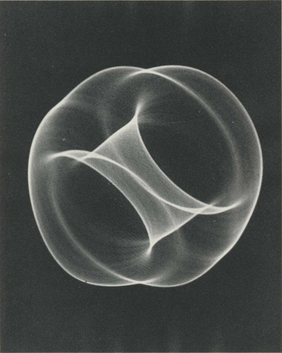 Ilustracja przedstawia pracę Bena Laposky'ego pod tytułem „Oscillon 40”. Dzieło prezentuje grafikę stworzoną za pomocą oscyloskopu. Grafika swoim kształtem przypomina jabłko.