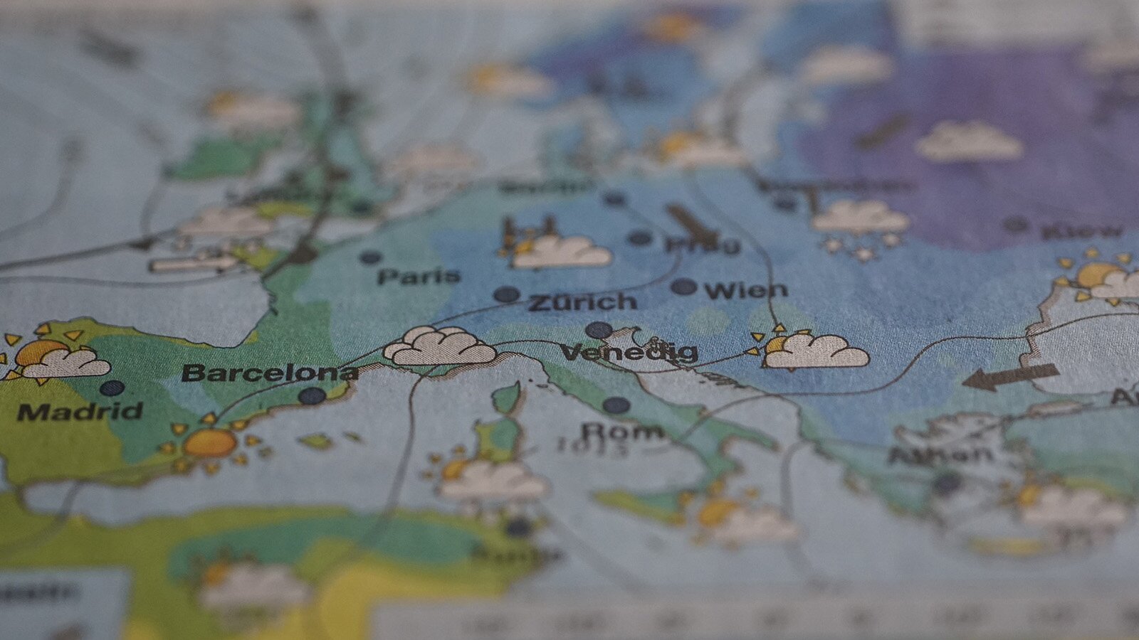 Zdjęcie przedstawia mapę Europy, z zaznaczonymi na niej w języku angielskim stolicami państw. Przedstawione są także fronty atmosferyczne oraz ikony reprezentujące takie warunki pogodowe jak opady atmosferyczne, zachmurzenie oraz wiatr.