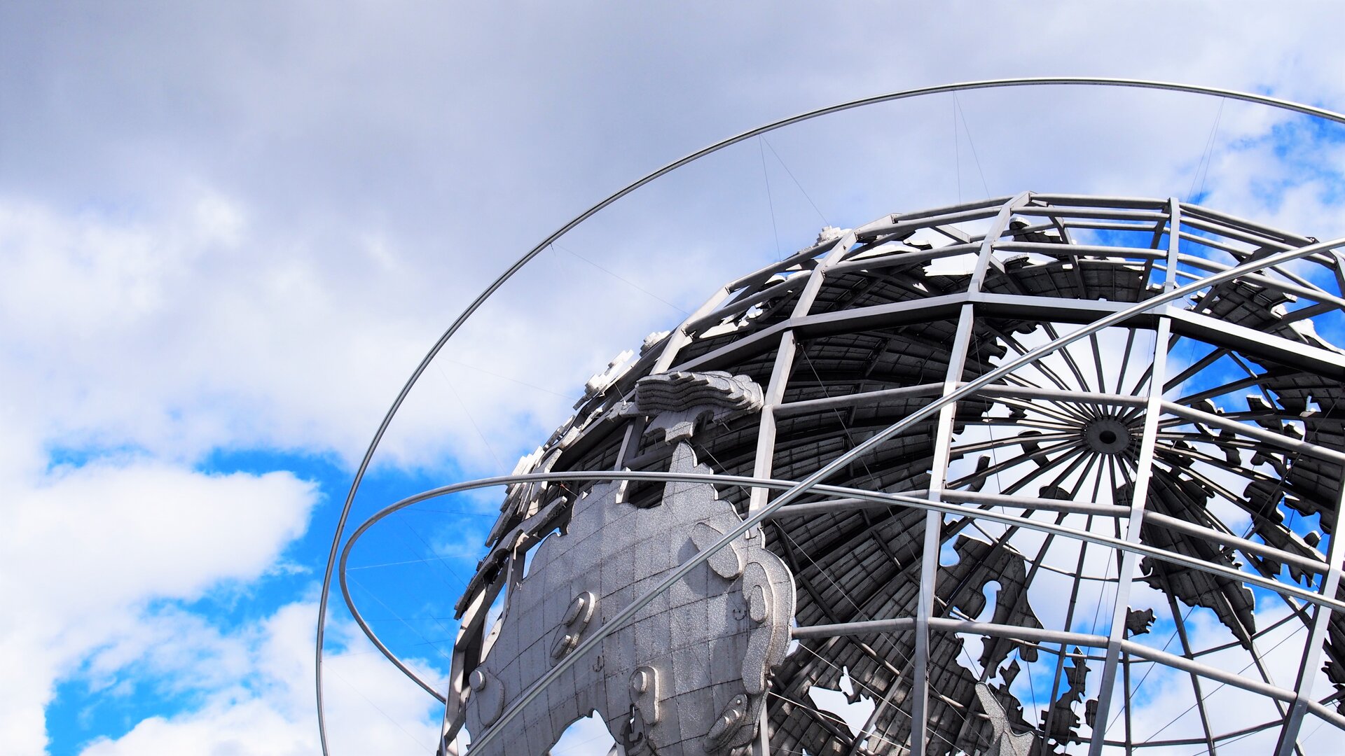 Zdjęcie przedstawia  metalowy model Ziemi, wokół której krążą metalowe orbity. Transkrypcja znajduje się poniżej.