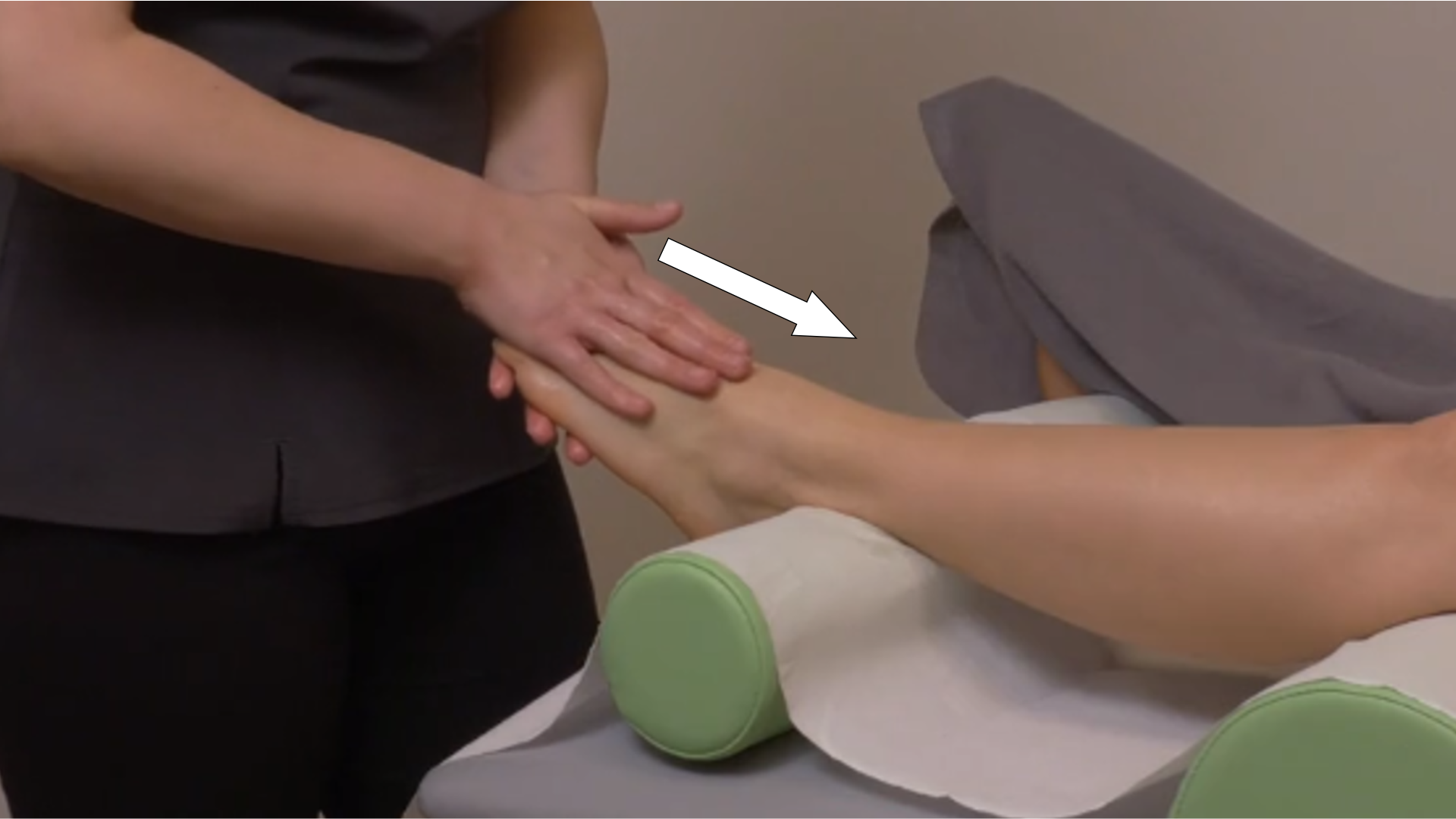 Zdjęcie pod tytułem głaskanie powierzchowne grzbietowej strony stopy. Zdjęcie przedstawia ręce masażystki wykonujące posuwiste ruchy opuszkami palców w kierunku od palców do kostki grzbietowej strony stopy pacjentki.