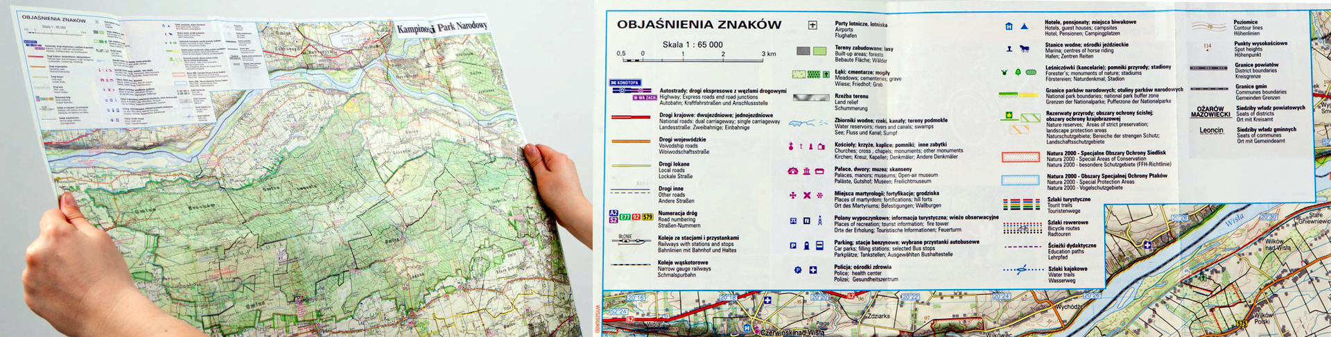 Zdjęcie przedstawia mapę turystyczną Kampinoskiego Parku Narodowego. Mapa ma kształt prostokąta. Mapa trzymana jest za boki, widać dwie dłonie po lewej i prawej stronie mapy. Dłuższe boki ułożone są poziomo. W lewym górnym rogu znajduje się legenda. Obok legenda przedstawiona jest w powiększeniu. Widać skalę - jeden do sześćdziesięciu pięciu tysięcy. Na mapie kolorowe przerywane linie oznaczają szlaki turystyczne. Na mapie zaznaczone jeziora, stawy i rzeki. Ponadto pola uprawne i tereny leśne. Szczyty są nazwane oraz podana jest liczba metrów opisanego wzniesienia. Cała mapa pokryta jest liniami, które ułożone są w formie pętli. Linie mają kształt falisty. Są to poziomice. Im mniejsza odległość między liniami tym powierzchnia terenu jest bardziej stroma.