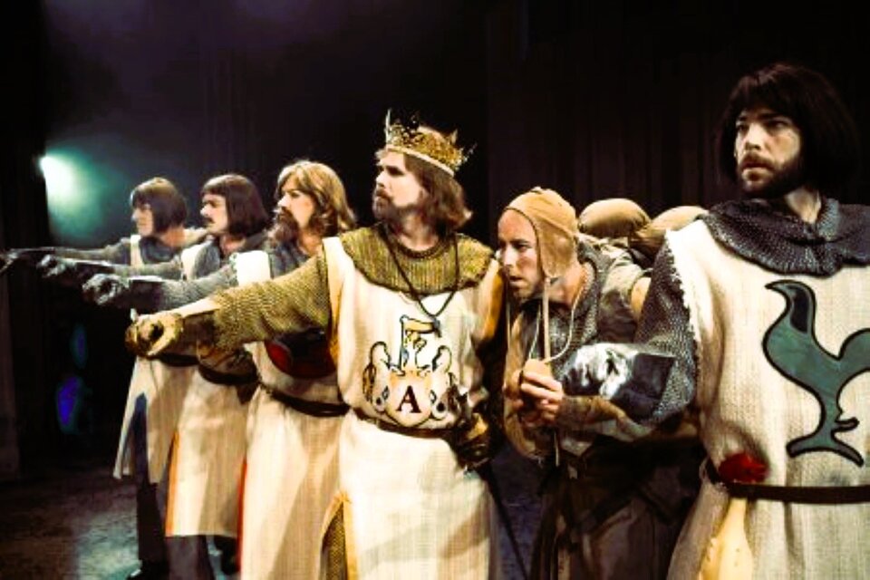 Zdjęcie przedstawia scenę ze spektaklu "Rycerze Graala'" duńskiego teatru  Odense Teater [czyt. odens titer]. Rycerze króla Artura wraz z samym królem stoją w rzędzie wzdłuż sceny z wyciągniętą prawą ręką w geście przysięgi. Tylko giermek obok króla wyróżnia się biednym ubraniem i służalczą, zgarbioną postawą.  Pozostali mają na sobie stroje rycerskie z epoki - kolczugę i herb na piersiach sukmany. Król Artur wyróżnia się koroną na głowie. 