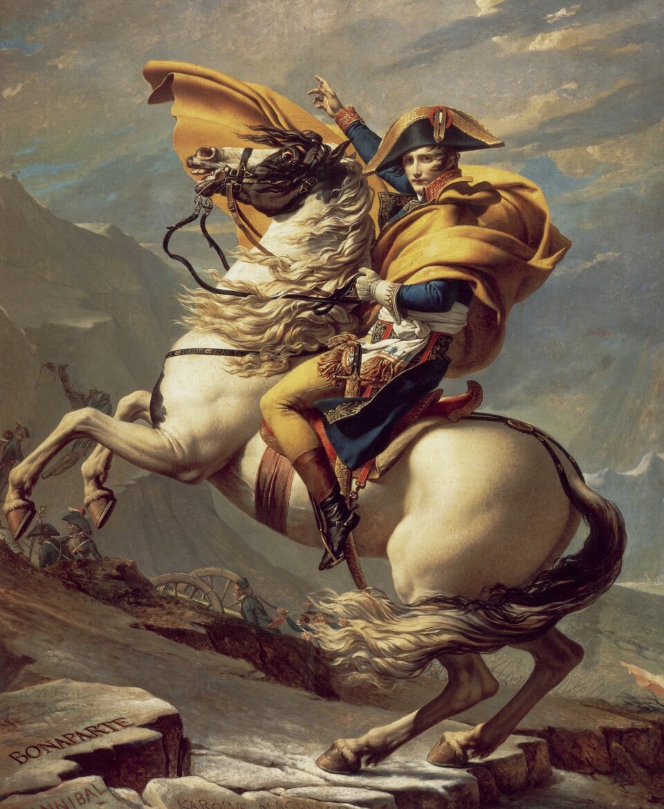 Ilustracja przedstawia obraz zatytułowany „Napoleon przekraczający Przełęcz św. Bernarda”, autorstwa Jacques’a‑Louisa Davida.
Obraz ukazuje mężczyznę siedzącego na wspiętym koniu. Koń unosi wysoko przednie nogi, a jego ciało jest napięte, jakby reagowało na silny podmuch. Jeździec ma na sobie długi płaszcz, który układa się w szerokie, falujące fałdy. Płaszcz jest wyrzucony w bok, tworząc wrażenie gwałtownego ruchu. Mężczyzna trzyma jedną rękę wyciągniętą przed siebie, w geście prowadzenia. Jego sylwetka jest stabilna, mimo dynamicznej pozycji konia. Tło tworzy skalisty teren i strome zbocza, które podkreślają trudność drogi. Cała scena jest zbudowana na silnym napięciu ruchu: koń wspina się, płaszcz wiruje, a postać jeźdźca pozostaje wyprostowana i zdecydowana.