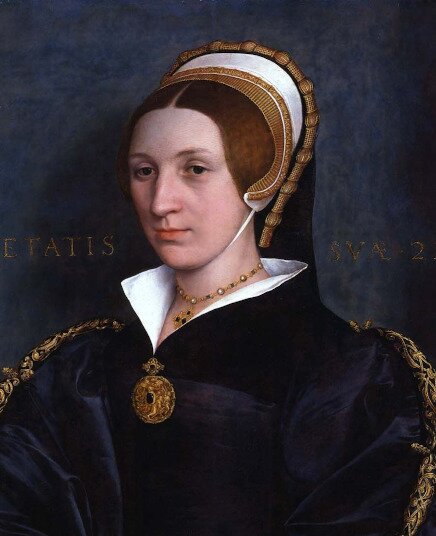 Ilustracja przedstawia portret Katarzyny Howard (1523/24‑1542) - piątej żony Henryka Ósmego. Kobieta ma zmęczoną twarz, podkrążone oczy, ziemistą cerę. Ma brązowe włosy. Ubrana w granatową szatę z białym kołnierzem. 