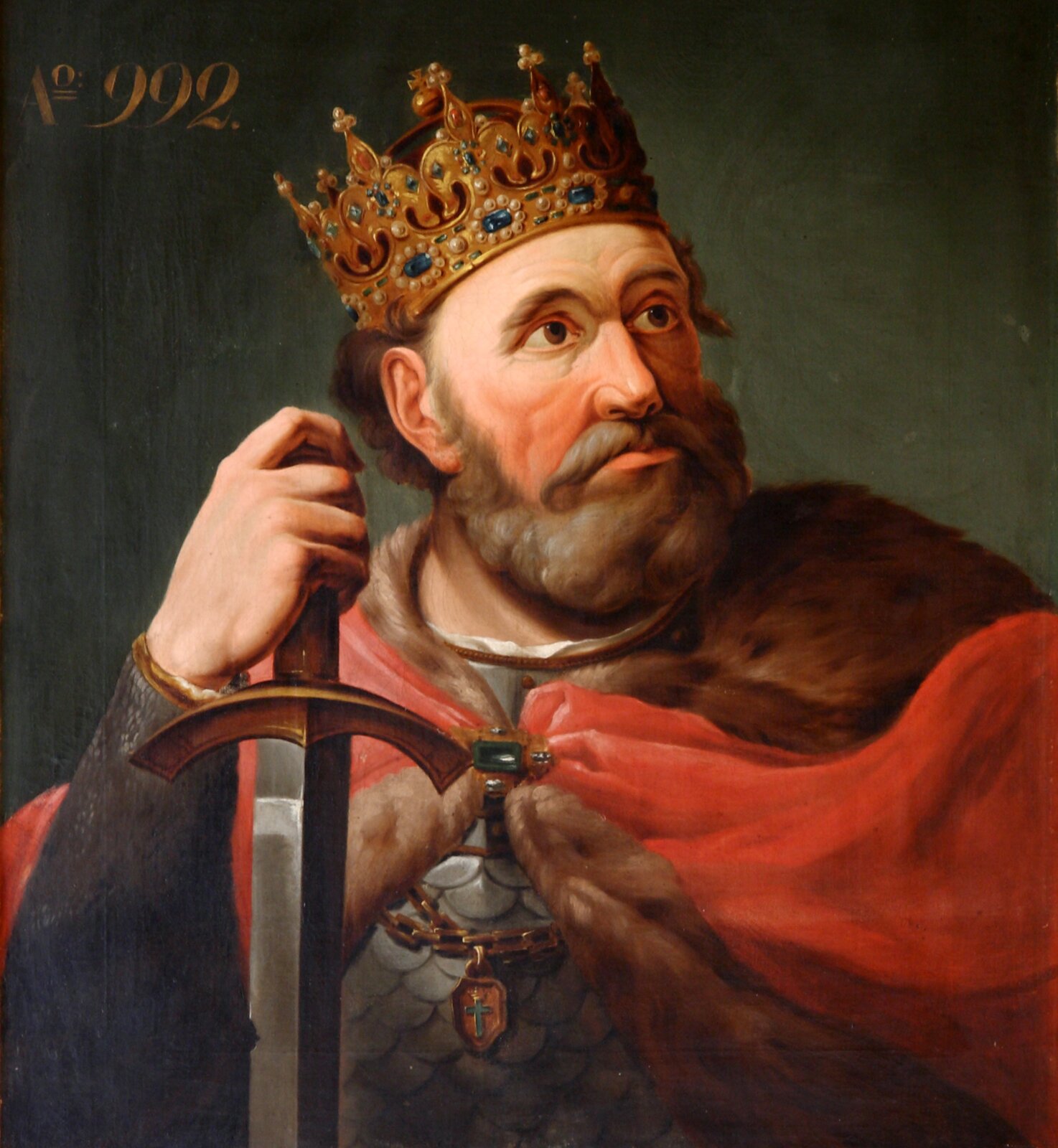 Kliknij żeby powiększyć Obraz przedstawia władcę ze złotą koroną wysadzaną drogocennymi kamieniami na głowie. Jest ubrany w karacenę. Na nią ma założony czerwony płaszcz z futrzanym podbiciem. Zdobi go złoto-zielona zapinka. Przy płaszczu znajduje się złoty łańcuch z wisiorkiem, w którym jest umieszczony srebrny krzyż ze złotą koroną. Wspiera się jedną ręką na mieczu. Spogląda w prawą stronę.