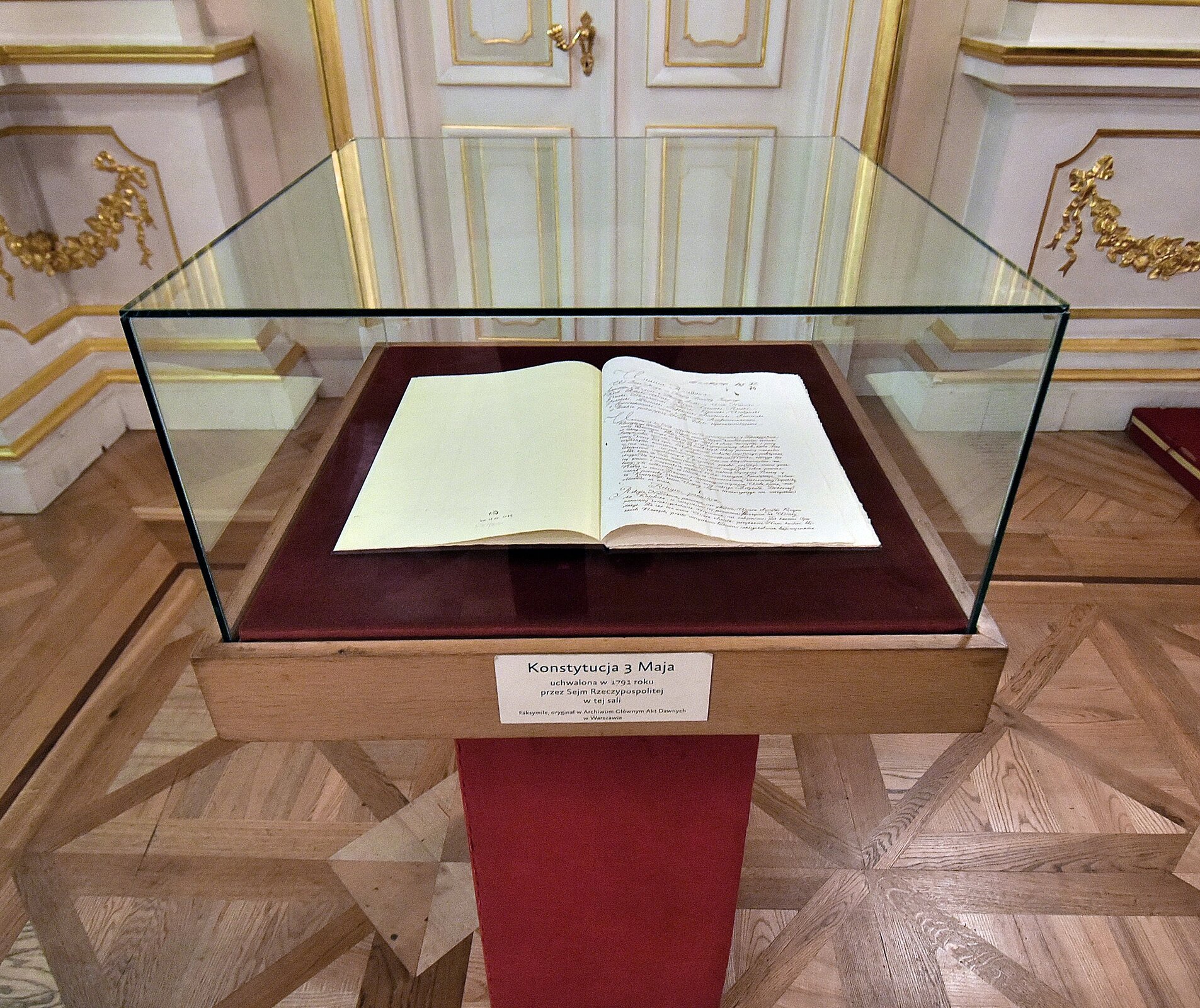 Fotografia barwna przedstawiająca kopię Konstytucji 3 maja eksponowaną w Sali Senatorskiej w Warszawie.