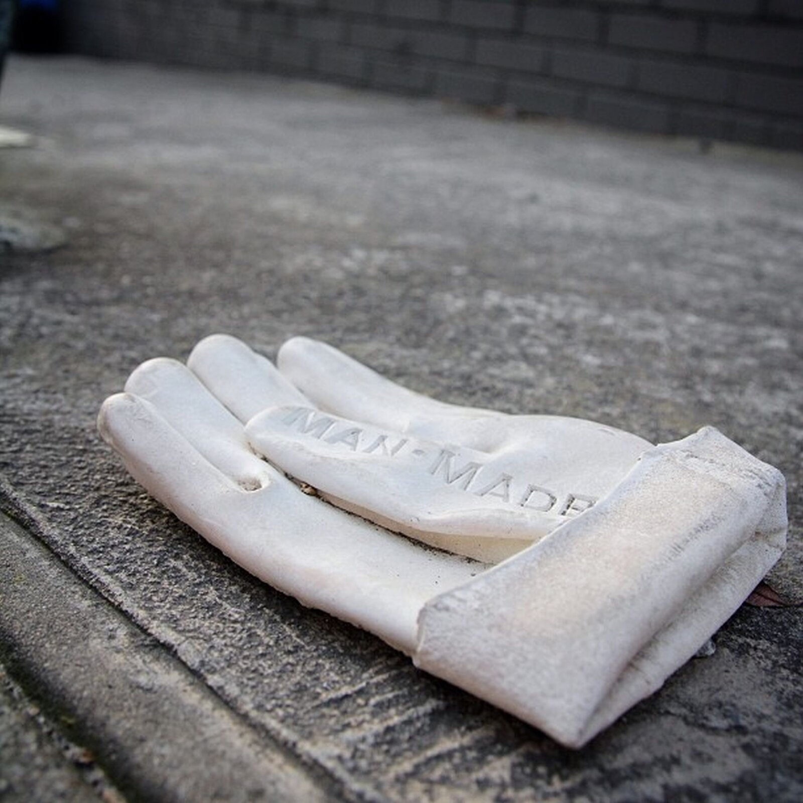 Ilustracja przedstawia rzeźbę Willa Colesa  „Man -made” . Ukazuje leżącą na chodniku białą rękawicę, wykonaną z żywicy. Rękawica jest podwinięta, a jej duży palec jest założony do środka. Na nim znajduje się napis MAN‑MADE, co oznacza- syntetyczny.