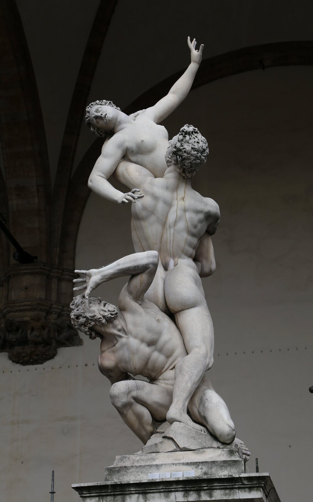 Rzeźba Giovanni da Bologna, „Porwanie Sabinek”. Dzieło przedstawia trzy postacie. Dwie z nich to mężczyźni. Jeden unosi kobietę do góry.