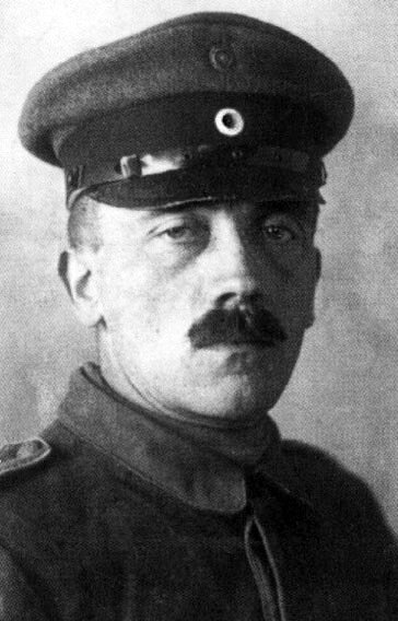 Kliknij, aby powiększyć Zdjęcie przedstawia Adolfa Hitlera. Przedstawiony jest powyżej wysokości ramion. Ubrany jest w mundur wojskowy. Na głowie ma czapkę wojskową. Na twarzy szerokie wąsy.