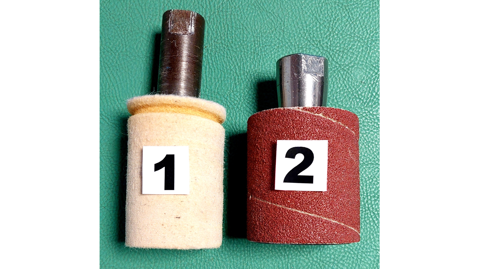 Zdjęcie przedstawiające dwa wałki osadzone na metalowch trzpieniach. Wałek jeden jest wykonany z materiału przypominającego korek, a wałek dwa jest pokryty papierem ściernym. 