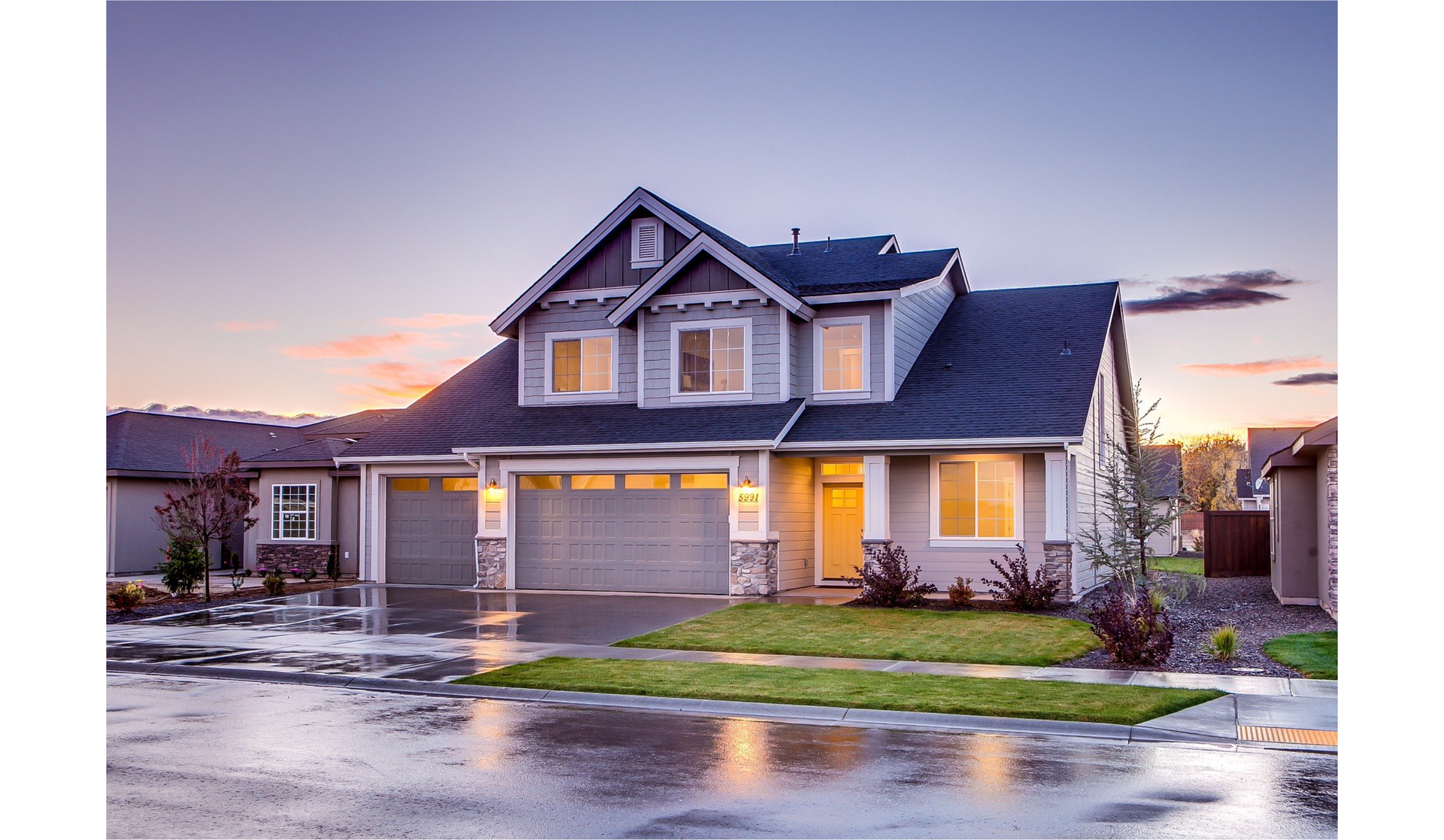 Ilustracja przedstawia duży dom z dwoma bramami garażowymi oraz wieloma oknami. 