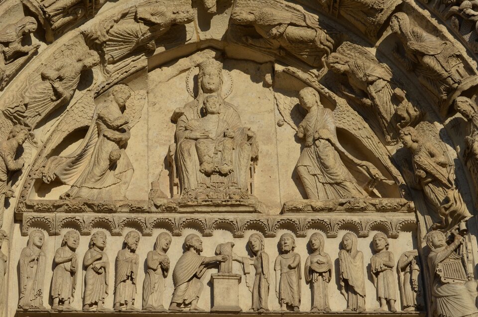 Ilustracja przedstawia prawy portal katedry w Chartres. Znajduje się na nim Maria z Dzieciątkiem oraz dwa anioły, trzymające w rękach kadzielnice. Pozy aniołów są lekko pochylone, dopasowane do łuku tympanonu. Pod rzeźbą, pod dekoracją arkadkową, znajduje się rząd postaci, pomiędzy którymi stoi stół ofiarny.  