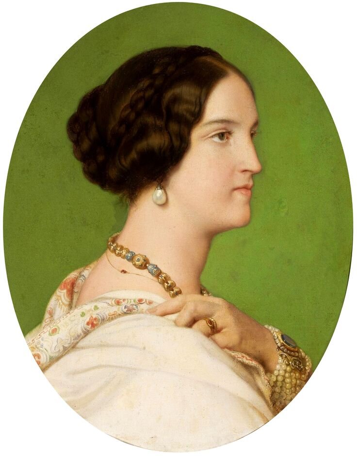 Obraz przedstawia portret młodej kobiety. Jest ukazany jej prawy profil. Kobieta ma długie, upięte na głowie włosy, duże kolczyki z perłami. Mały nos i wąskie usta. Ubrana jest w suknię, na szyi ma naszyjnik, na lewej dłoni dużą bransoletę z pereł. 
