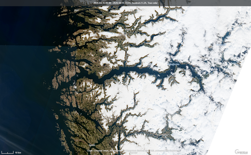 Ortofotomapa przedstawia fiord Sognefjorden w zachodniej Norwegii. W centralnej części widoczna jest szeroka odnoga fiordu, od której odchodzą liczne węższe ramiona głęboko wcinające się w górzysty ląd. Góry są w większości pokryte śniegiem, a miejscami odsłaniają się skaliste stoki i doliny. Po lewej stronie rozciąga się Morze Norweskie z licznymi skalistymi wyspami i wysepkami u wybrzeża. Na obrazie widoczna jest podziałka 10 km oraz informacje o zobrazowaniu satelitarnym Sentinel‑2 z 15 kwietnia 2026 r.