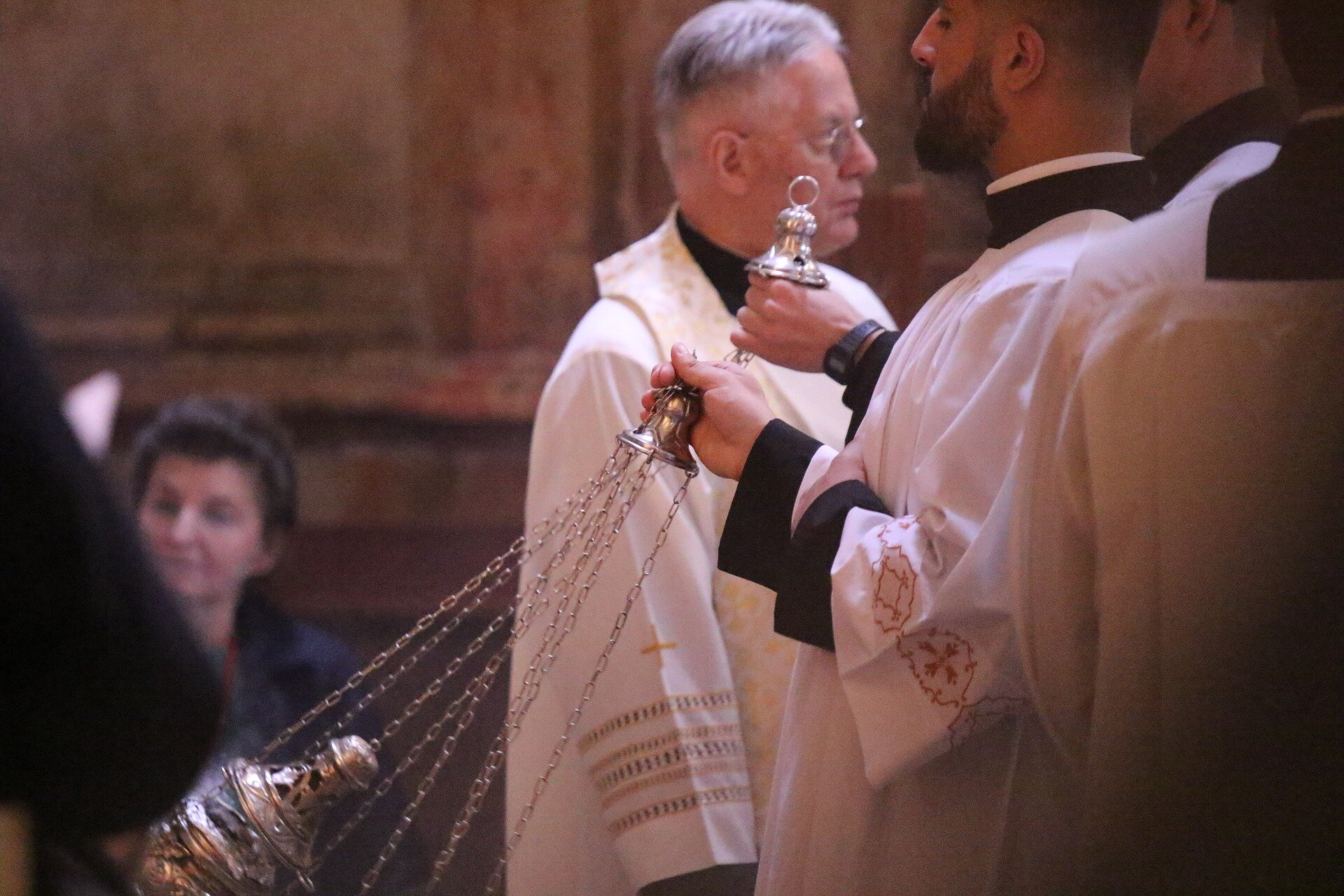 Zdjęcie przedstawia kilku duchownych w białych szatach. Jeden z nich macha kadzidłem.