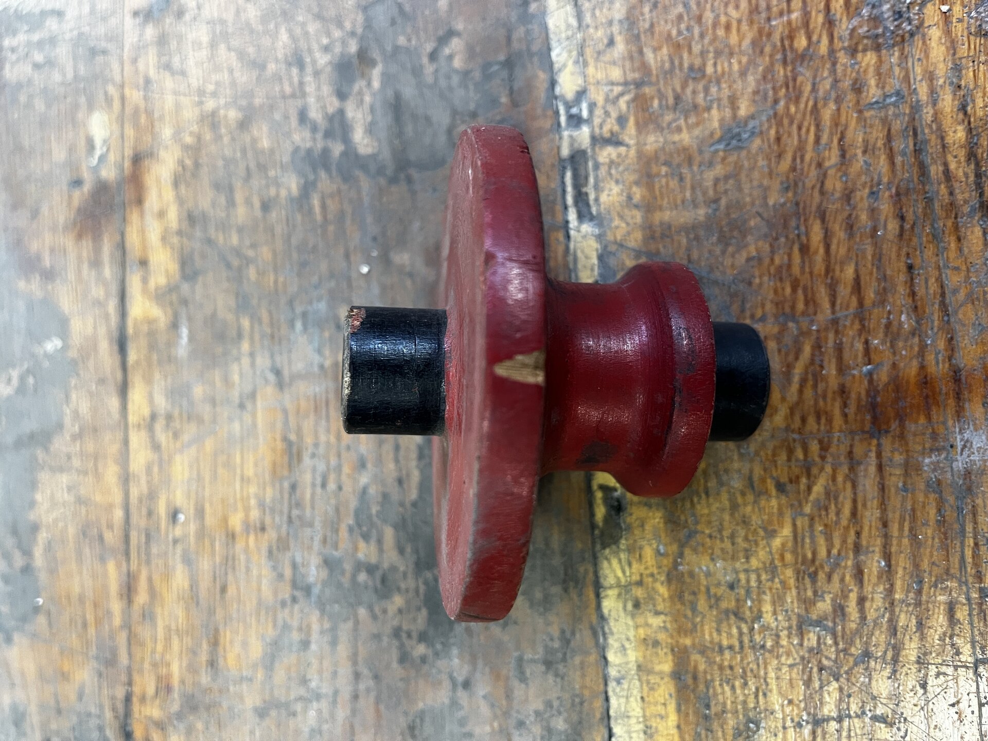 Na zdjęciu pokazano drewniany model odlewniczy z widocznym pęknięciem i ubytkiem materiału. Przedstawiony model ma kształt bączka. Do dolnym szerszym okręgu modelu widoczny jest ubytek materiału o kształcie klina. Na dole na elemencie stanowiącym okrągły rdzeń widoczne jest pęknięcie. Pęknięcie biegnie po obwodzie elementu. 