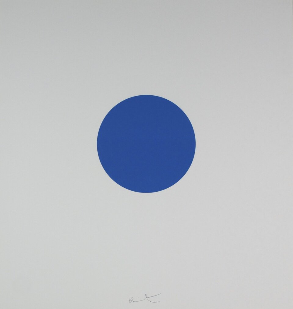 Ilustracja przedstawia pracę autorstwa Damiena Hirsta pod tytułem „Pridinol”. Praca prezentuje szare tło, na którym znajduje się niebieska kropka. 