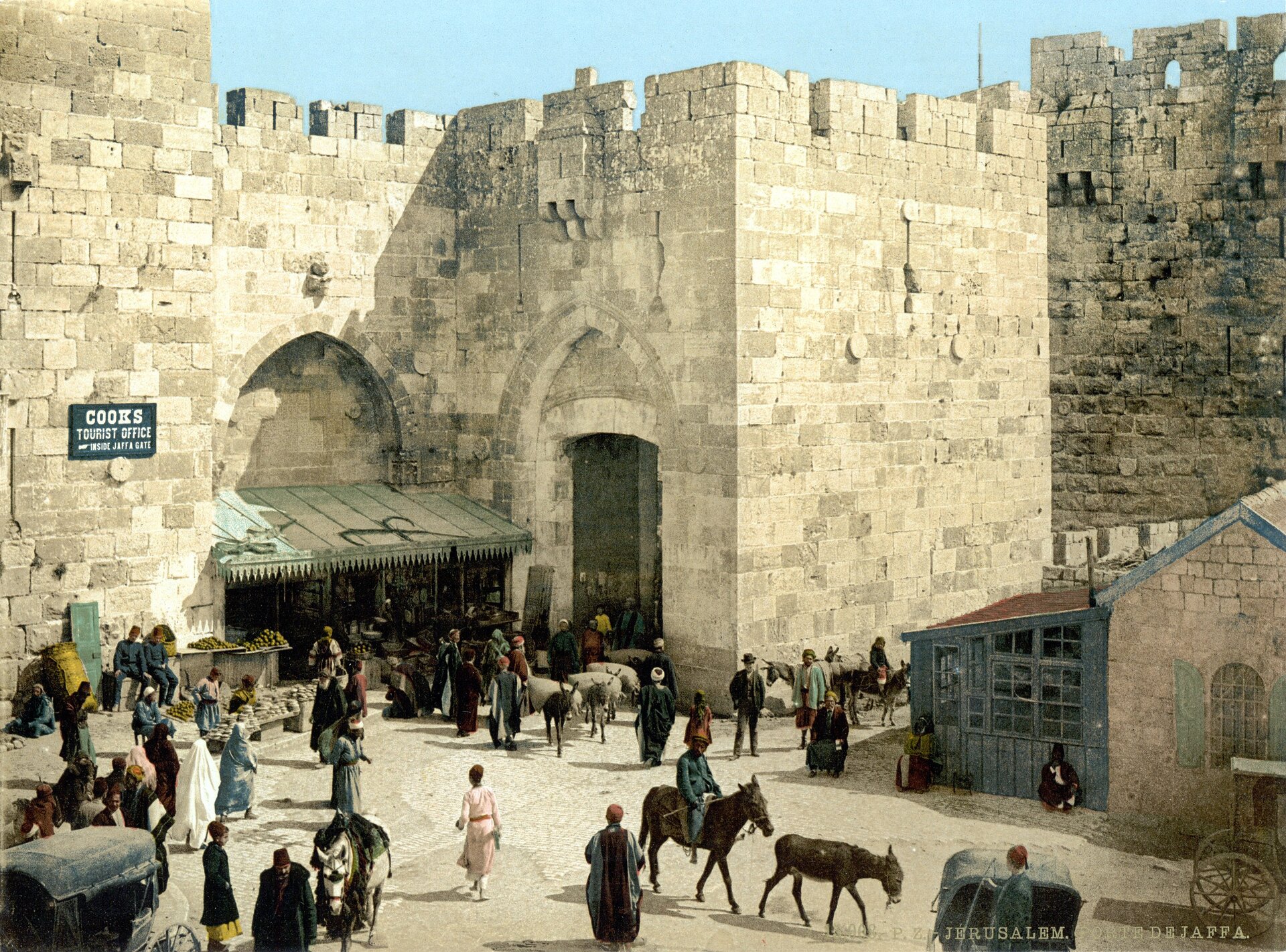 Ilustracja przedstawia obraz placu handlowego w Jerozolimie. Na placu znajdują się stragany, po placu spacerują kupujący oraz handlarze ciągnący zwierzęta. Wszyscy ubrani w charakterystyczne, arabskie stroje. Plac otaczają ceglaste mury Jerozolimy.