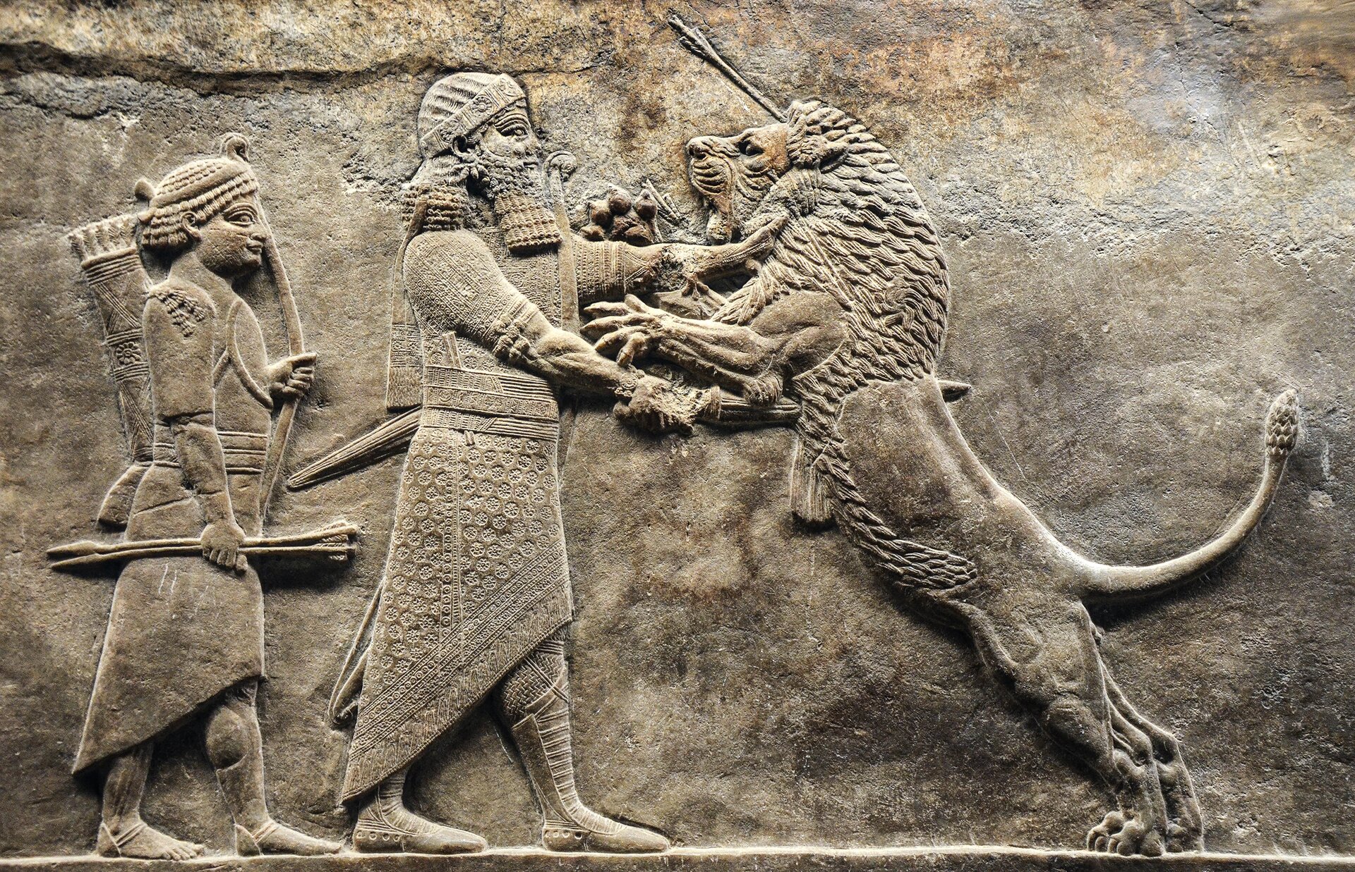 W centralnym miejscu płaskorzeźby  jest król asyryjski, który rękoma powstrzymuje skaczącego na niego, agresywnego lwa. Za królem stoi wojownik, w ręku ma strzały i łuk. 