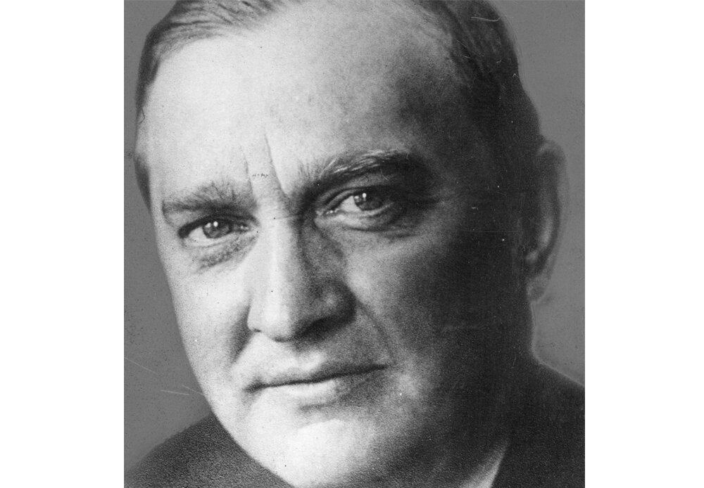 Czarno-biała fotografia przedstawiająca zbliżenie na twarz Stefana Banacha. Patrzy wprost w obiektyw, widać zmarszczkę między brwiami. Ubrany jest w ciemny garnitur i koszulę.