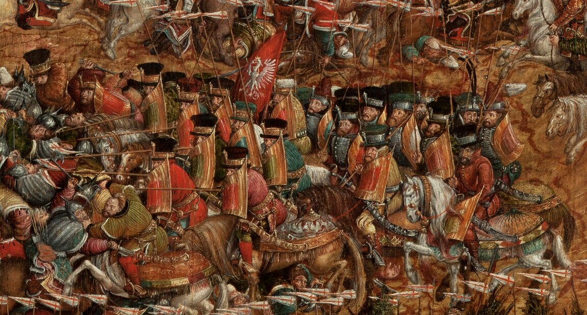 Kliknij, aby powiększyć Obraz przedstawia żołnierzy znajdujących się na koniach. Na głowie mają wysokie czapki, a w dłoni długie drewniane elementy uzbrojenia. Nie są opancerzeni. Żołnierze ubrani są w kolorowe szaty. Widać czerwoną flagę z białym orłem. Przed nimi są miażdżeni żołnierze w spiczastych hełmach.