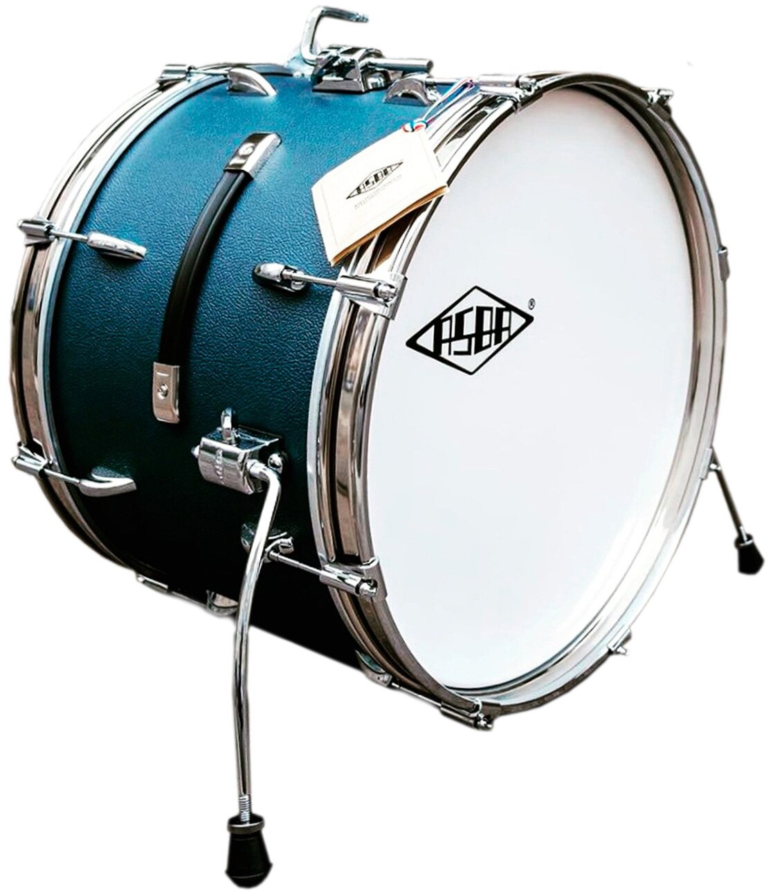 Zdjęcie przedstawia bęben centralny. Przedmiot ma kształt walca w ujęciu trzy czwarte. Pośrodku walec ma kolor niebieski metalizujący, a na obydwu końca walcach znajdują się srebrne okrągłe obręcze ze srebrnymi, poziomo usytuowanymi zaczepami. Pośrodku bębna widoczny jest pionowy czarny uchwyt, na obu końcach którego są dwa srebrne prostokąty – zaczepy. Frontalna część walca ma biały kolor, z logo z czarnych liter ASDA wpisanych w biały romb o bokach w kolorze czarnym. Po obu stronach bębna, w dolnej jego części, widoczne są dwie srebrne nóżki, zakończone czarnymi półkolistymi elementami.