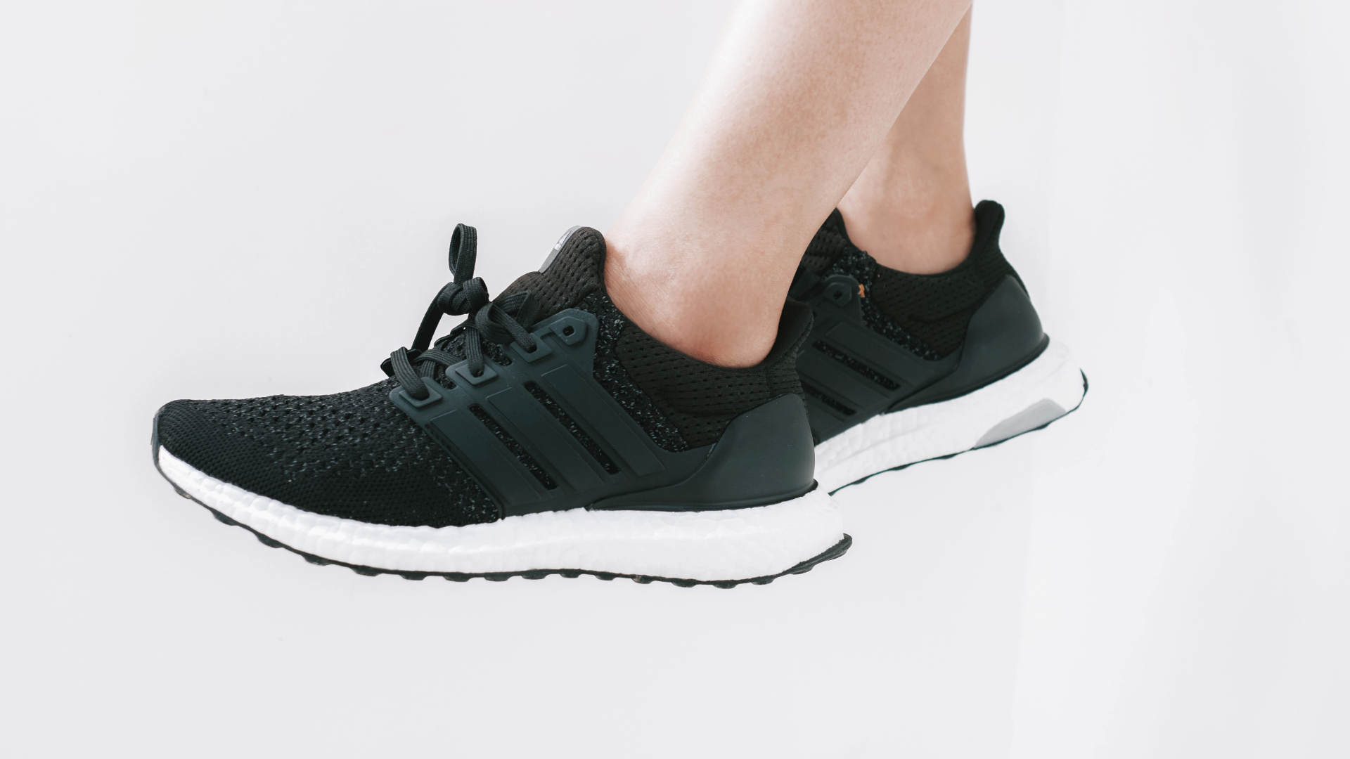 Zdjęcie przedstawia buty sportowe w ciemnym kolorze. Buty ma na sobie osoba, której widoczne są tylko łydki.