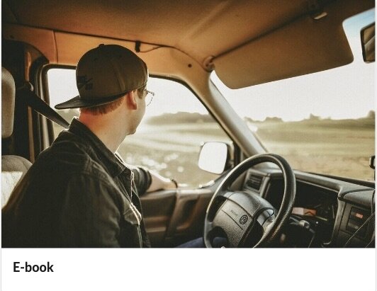 Zrzut ekranu przedstawia przykładową okładkę e‑booka. Widoczne jest zdjęcie z podpisem e‑book. Na zdjęciu pokazane jest wnętrze samochodu dostawczego. Za kierownicą siedzi mężczyzna w czapce, patrzący z dala od aparatu przez okno.