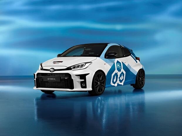 Ilustracja przedstawia samochód z silnikiem napędzanym wodorem. Znajduje się on prawdopodobnie na wystawie. Jest biało‑niebieskiego koloru. Jest to samochód typu hatchback.