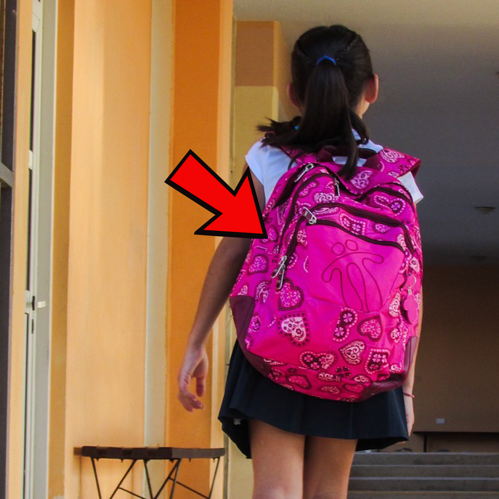 Ilustracja przedstawia plecy dziewczynki, a czerwona strzałka wskazuje plecak, który nosi. 