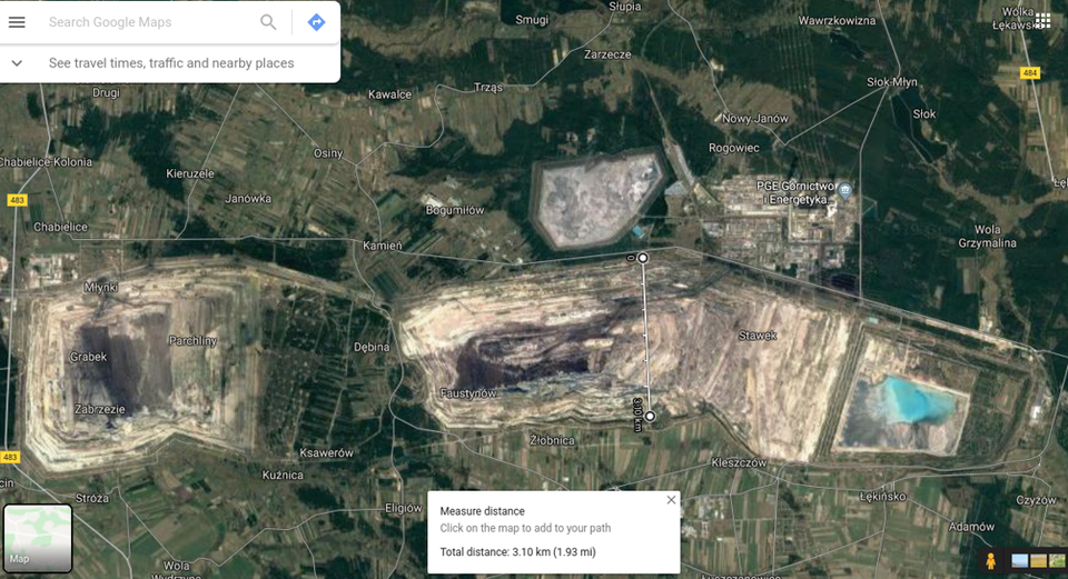 Satelitarne zdjęcie przedstawia odkrywkę bełchatowską. Na zdjęciu widać zmierzoną na całej szerokości odkrywkę długości 3,1 km przy użyciu narzędzi oferowanych przez Google Maps. Odkrywka z lotu ptaka składa się z kilku geometrycznych, jasnożółtych  kształtów umieszczonych jeden koło drugiego, które układają się w jeden ciąg. Dookoła występują ciemnozielone lasy i jasnozielone tereny trawiaste. 