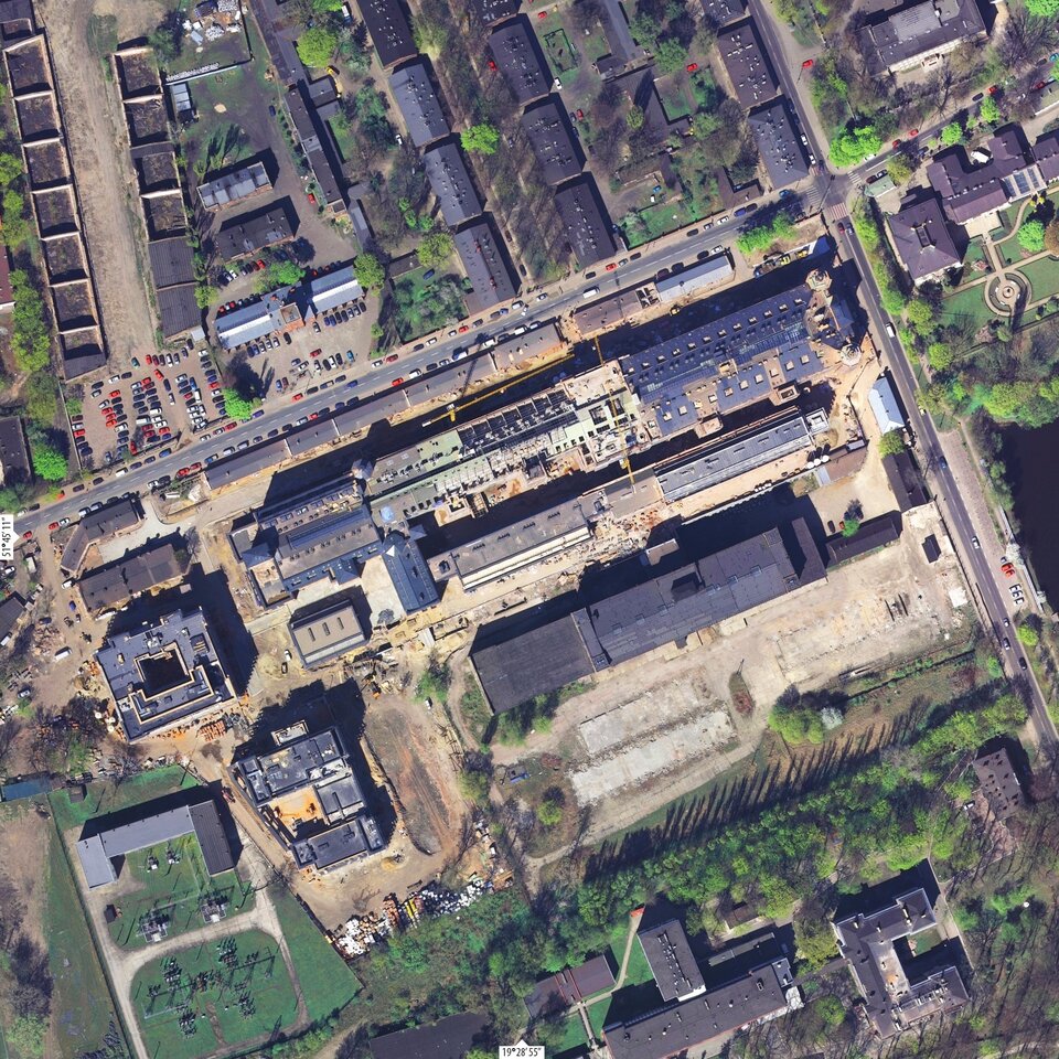 Ilustracja przedstawia zdjęcie z lotu ptaka na Lofty "U 
Scheiblera" w Łodzi. Są to luksusowe apartamenty w pobliżu zabytkowych fabryk i  domów robotniczych z XIX wieku. Są to podłużne budynki, są one regularnie rozłożone. 