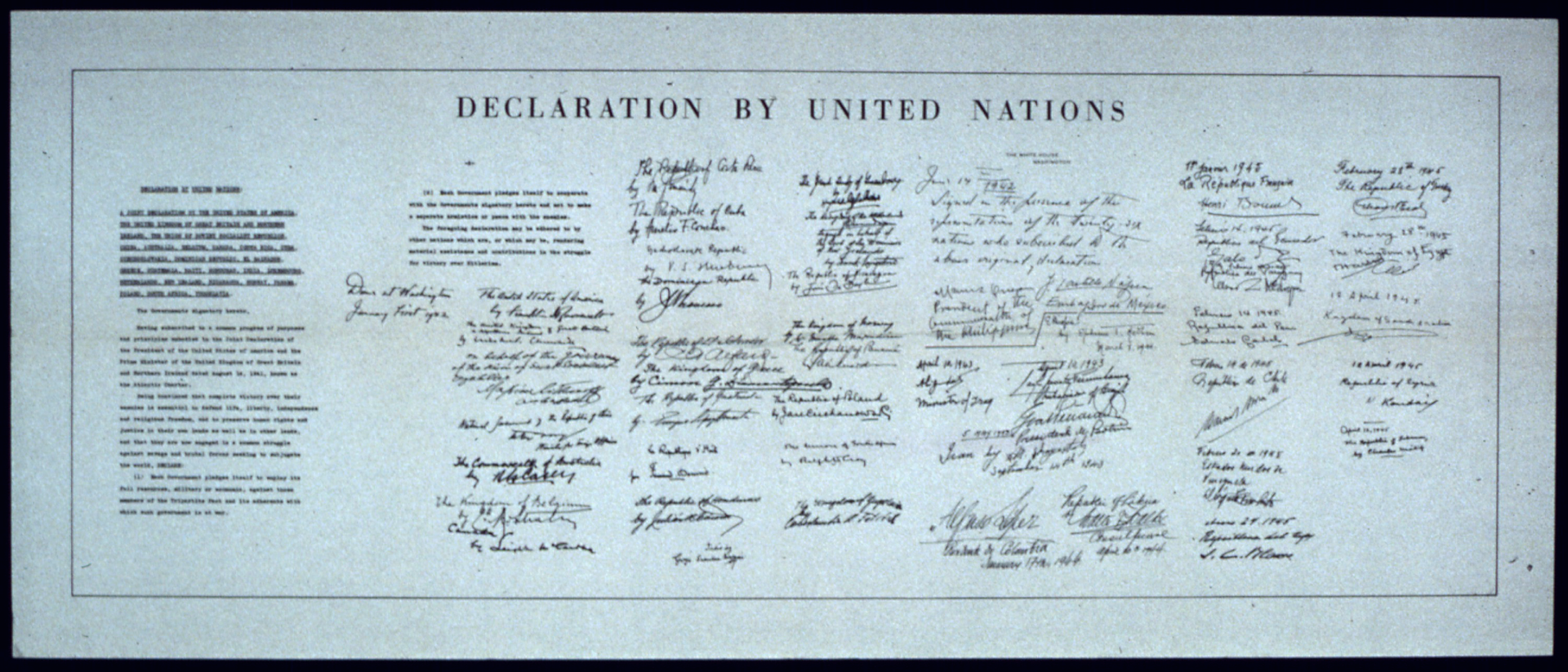 Ilustracja przedstawia duży papierowy dokument. To biało-czarne zdjęcie karty Narodów Zjednoczonych. Na górze dokumentu poziomy napis w języku angielskim: Declaration by United Nations. Po lewej stronie treść deklaracji w dwóch kolumnach. Na prawo od treści 26 podpisów wykonanych przez przedstawicieli państw członków założycieli. Podpisy ułożone są w 7 kolumnach. Kolumny jedna obok drugiej.