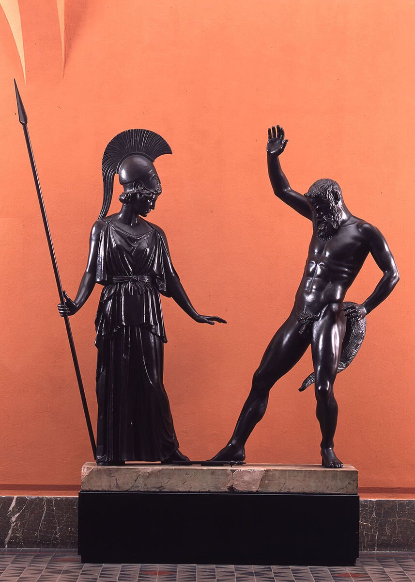 Ilustracja interaktywna przedstawia grafikę, ukazującą rzeźbę „Atena i Marsjasz”, autorstwa Myrona. Zdjęcie ukazuje dwupostaciową rzeźbę wykonaną w brązie. Ustawiona po lewej stronie postać Ateny z nasuniętym na czoło hełmie z wysokim pióropuszem oraz związanej na biodrach drobno pofałdowanej todze, wspiera się prawą ręką na włóczni. Pochylona głowa oraz gest wyciągniętej w dół lewej dłoni wskazują na to, że przed chwilą upuściła flet leżący na ziemi. Po prawej stronie ukazany został Marsjasz. Jest to nagi, brodaty mężczyzna. Ukazana w dynamicznej pozie postać odchylona jest do tyłu. Tułów wspiera się na ugiętej lewej nodze, głowa skierowana jest w dół. Marsjasz patrzy na flet, który właśnie ujrzał. Prawą rękę ma wzniesioną, jak gdyby chciał szybkim gestem go podnieść. Rzeźba umieszczona została na tle ściany w kolorze ciepłej czerwieni. Po wybraniu grafiki zostanie wyświetlona informacja dodatkowa. O wielkości tego artysty świadczą zachowane w postaci rzymskich kopii dwa dzieła: „Dyskobol” oraz „Atena i Marsjasz”. O pozostałych rzeźbach wiemy niewiele i to tylko dzięki przekazom starożytnych poetów. Artysta, znany z perfekcji technicznej, był mistrzem dynamicznej rzeźby realistycznej. Najczęściej przedstawiał postacie bogów, herosów, a także atletów. Przykładowo rzeźba „Atena I Marsjasz” przedstawia młodą boginię w peplosie, z włócznią i w hełmie, która rzuca właśnie flet (aulos) przed Marsjasza, który lekko się odchylając, wznosi prawą rękę do góry. Jego postawa może być interpretowana jako próba podchwycenia fletu lub wręcz przeciwnie, strachu przed podjęciem instrumentu. Strach ten sygnalizuje przyszłość Marsjasza, który po przegranym pojedynku z Apollem (Marsjasz grał na flecie, a Apollo na kitarze) został przez niego odarty ze skóry.