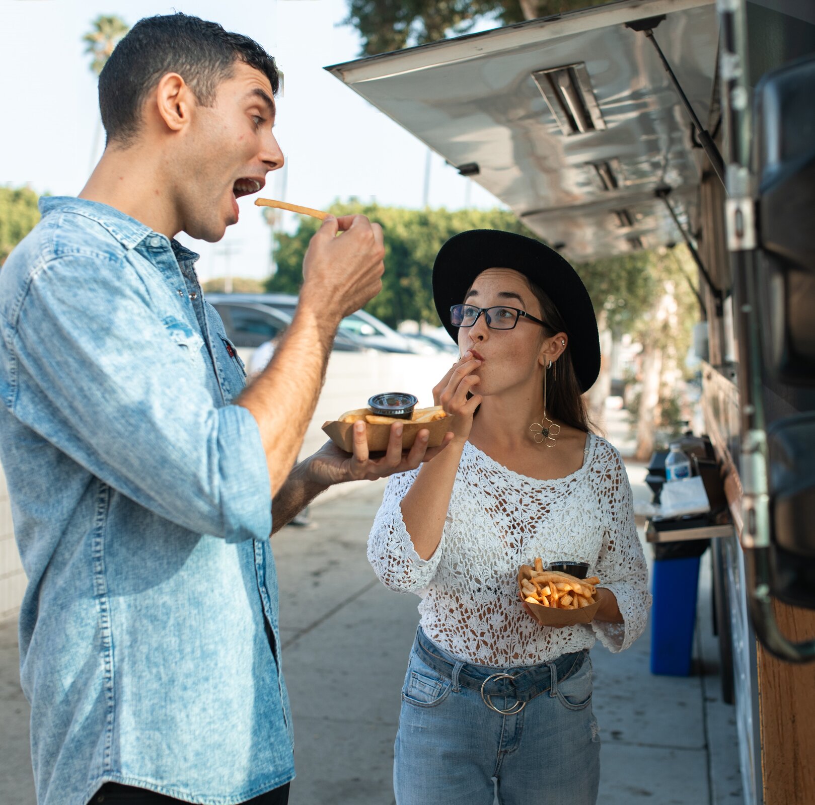 Na zdjęciu widać kobietę i mężczyznę jedzących frytki umieszczone na papierowych tackach.