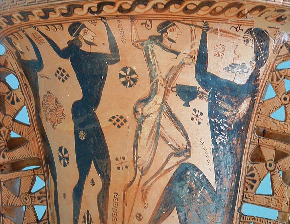 Zdjęcie przedstawia amforę czarnofigurową. Prezentuje kilku mężczyzn. Jeden z nich oślepia stojącego przed nim mężczyznę ostrym narzędziem. Oślepiony mężczyzna trzyma w prawej ręce kielich. Za plecami agresora znajdują się jeszcze dwaj mężczyźni.