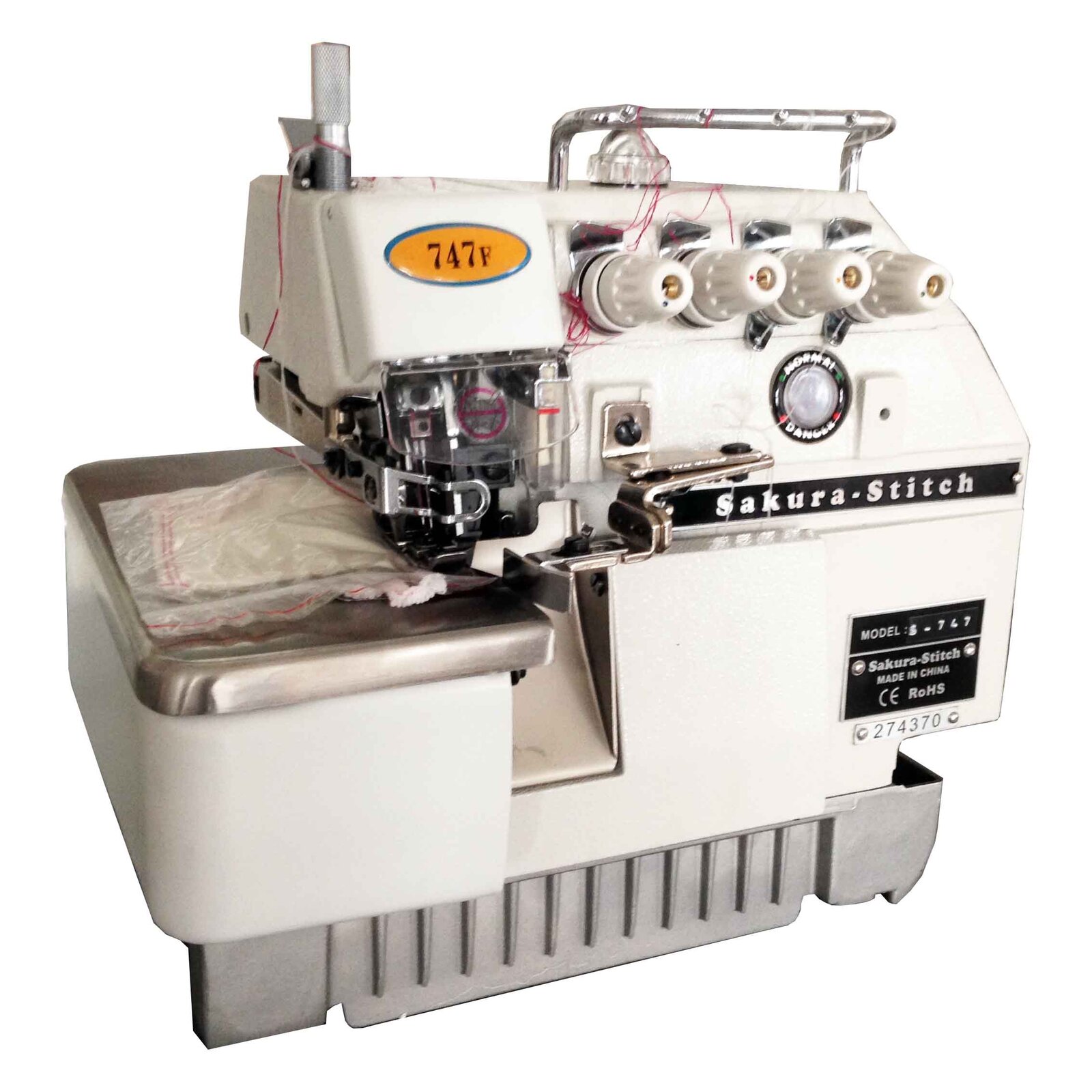 Na zdjęciu przedstawiono maszynę do szycia typu owerlok. W dolnej części urządzenia znajduje się blat oraz pojemnik na ścinki, nieco wyżej mieści się mechanizm szyjący, a na górze pokrętła regulacji naprężenia nici.