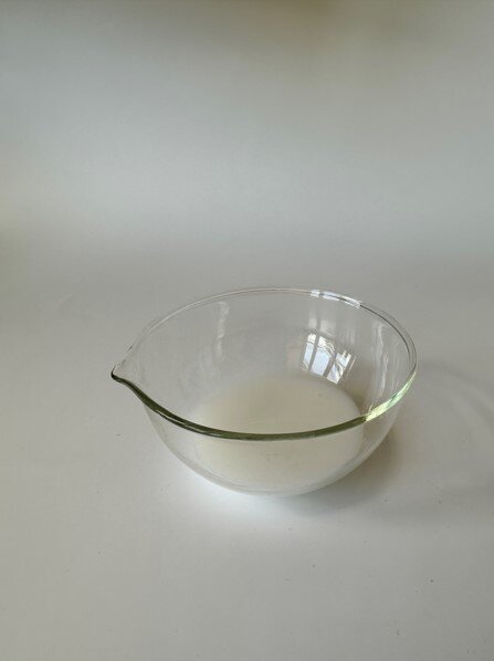 Zdjęcie przedstawia szklaną miskę z białą cieczą - polimerem bezrozpuszczalnikowym.